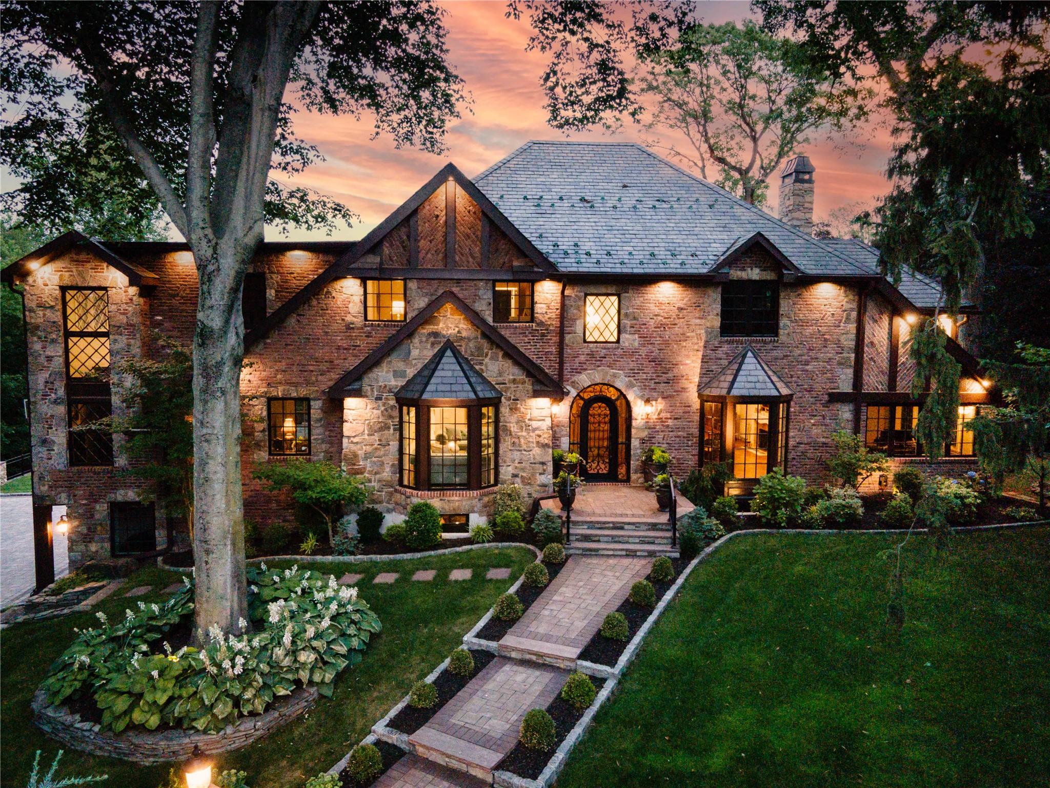 An architectural standout nestled on a quiet cul-de-sac within Manhasset’s coveted Strathmore Vanderbilt enclave, 38 Soundview Crest is a rare gem offering the perfect blend of timeless Tudor elegance and modern-day luxury across a spectacular .84-acre setting. Impeccably redesigned and masterfully expanded, this exceptional residence combines enduring architectural charm with today’s refined comforts. Greeting you upon arrival is a newly completed landscape and hardscape plan, featuring curated accent lighting, elegant stonework, and mature specimen trees that surround the home in natural beauty. Inside, a soaring two-story foyer opens to expansive living and entertaining areas, including a formal living room, a gracious dining room with fireplace, and a striking two-story family room with soaring, double-height paned-glass windows and French doors opening to the patio. The chef’s kitchen is both stunning and functionally designed, with modern beige cabinetry, premium appliances, a showcase butler’s pantry, and two sets of French doors leading to an expansive flagstone patio and connected yet distinct backyard areas ideal for entertaining or enjoying quiet moments outdoors. A beautifully finished marble full bath and a versatile main-level bedroom currently used as a home office offer flexible lifestyle options suited to today’s needs. The primary suite is a peaceful retreat with a spacious walk-in closet and a spa-inspired marble bath featuring a freestanding soaking tub. A second ensuite bedroom plus two additional bedrooms served by a shared marble bath complete the second floor with comfort and style. The legally finished walkout lower level enhances this home’s versatility, featuring a large recreation space, oversized glass doors that welcome in natural light, a full laundry room, mechanicals, and direct access to a rarely offered 3-car garage adjacent to an oversized storage room. This level is ideal for guest recreation, fitness, multi-use entertainment, and exceptional storage. Outdoors, the professionally designed, meticulously manicured grounds offer privacy, beauty, and generous space perfect for play, gatherings, lounging, or creating your own outdoor retreat. The expansive rear yard is large enough to accommodate a pool, presenting a rare opportunity to establish a true resort-like setting at home. Ideally located in close proximity to the Strathmore Vanderbilt Country Club (membership required) and just minutes from the Manhasset LIRR, town, world class shopping, dining, and major highways and hospitals, this is a truly remarkable opportunity to own a reimagined classic in one of the North Shore’s most coveted neighborhoods.