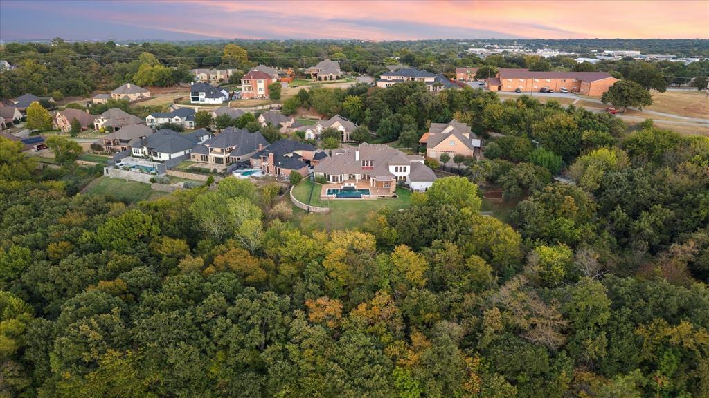 MULTIPLE OFFERS RECEIVED. Seller calling for highest, best by 12PM Monday, Oct. 27. Showstopping estate where elegance, privacy and modern updates meet on nearly two acres w no backyard neighbors. Custom-built residence offers over 6,600 SqFt of beautifully designed living space. Thoughtfully crafted w architectural detail at every turn; home combines timeless design w today’s luxury finishes. Grand double-door entry welcomes you into foyer w soaring ceilings and abundant natural light. Formal living and dining areas set stage for entertaining, while private study w built-ins provides perfect work-from-home retreat. At heart of home is chef’s kitchen - completely remodeled in 2018 w granite countertops, massive island, commercial-grade ss appliances, gas range, double ovens and built-in refrigerator. Kitchen opens to a spacious family room w stone fireplace and large windows overlooking serene backyard. Primary suite is retreat unto itself w sitting area plus fireplace, spa-inspired bath w freestanding tub, dual vanities, double shower and designer lighting. Upstairs, large game room w tray ceiling, 2nd primary suite w stunning view off of attached balcony and 2 more generously sized bedrooms w walk-in closets. Step outside to your private paradise — a spectacular outdoor living area w covered patio, stone fireplace, built-in grill and bar seating. Heated infinity-edge pool and spa overlook lush trees, offering unmatched sense of peace and seclusion. W no backyard neighbors and sweeping sunset views, it’s perfect setting for gatherings or quiet evenings by the fire. Additional highlights include electric gate entry, four-car garage, energy-efficient updates and smart-home capabilities. Property offers best of both worlds — a tranquil retreat w convenient access to major highways, shopping, dining and entertainment in heart of North Arlington. Experience luxurious living at its finest — where every detail reflects quality, comfort and sophistication.
