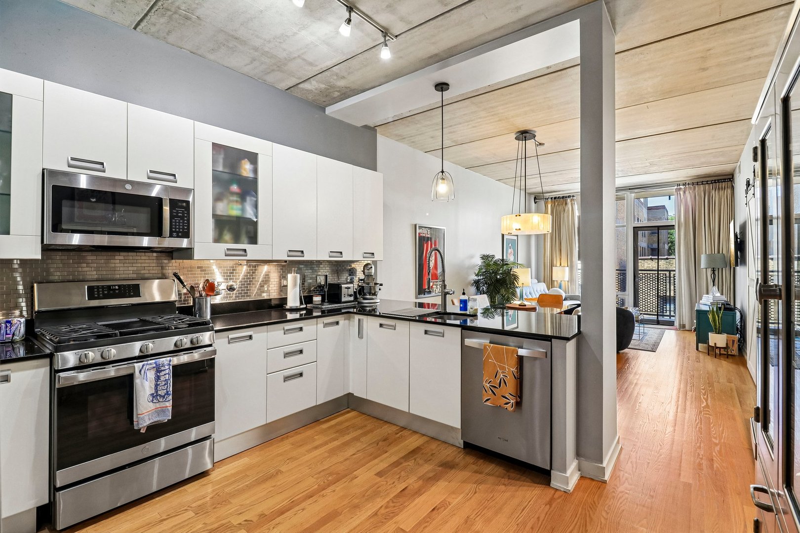 *** $5,000 SELLER CREDIT! Use it toward closing costs or a potential interest rate buydown, subject to lender approval. ***  Picture ending the day on your own oversized west facing balcony as the sun sets, with Foster Beach and the lakefront just a short walk away. This 2 bedroom, 2 bathroom Edgewater soft loft pairs the character of a loft with the comfort of a true home.  Inside, 11 foot exposed concrete ceilings, real hardwood floors, and floor to ceiling windows bring in lots of natural light. The open kitchen flows straight into the living area, making entertaining easy. It features white Italian cabinetry, black granite countertops, stainless steel appliances, a stainless steel subway tile backsplash, and a breakfast bar. The custom bar in the kitchen nook stays, along with most of its contents, so you can host your first gathering the day you move in. All kitchen light fixtures are also included.  The oversized primary suite has room to spread out, great natural light, generous closet space, a sliding barn door, and a private bath with a shower remodeled within the last four years. The second bedroom, featuring bifold doors, works easily as a guest room, home office, or den. Recent updates include wallpaper in the entry and primary bedroom within the last two years and refinished balcony flooring. A separate laundry and utility room with a full size washer and dryer adds storage and everyday convenience.  Heated garage parking means no scraping windshields in January! Guest parking is also available. The contemporary concrete building offers a rooftop deck with beautiful Lake Michigan views and a green roof. A separate ground level dog run with K9 turf makes quick outings easy, and up to two pets are welcome.  Beyond your door, you'll find Mariano's just a few blocks away, with Whole Foods, Target, and Andersonville's restaurants and shops close by.  The newly rebuilt Bryn Mawr Red Line station and convenient Sheridan Road bus service make getting around the city easy. Well run and professionally managed association.  Furniture is negotiable for purchase, with the exception of the blue chair and silver cabinet in the kitchen.  *** SELLER OFFERING A $5,000 CLOSING CREDIT! ***