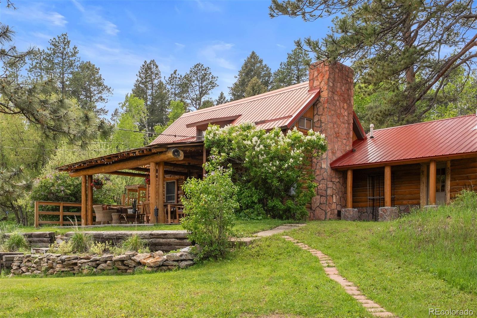Rare rideout property with TWO homes where the forest breathes, time lingers, and the trail never ends—this is more than land, it’s a legacy. Providing 5 beds, 4 baths, and 3,538 sf combined, it’s ideal for multigenerational living, retreat-style use, or simply welcoming others to savor the quiet. Set in the foothills of Sedalia, this 11-acre historic homestead boasts rare backdoor access to Pike National Forest and 500 miles of the Colorado Trail. Whether it’s horseback riding, snowshoeing, or watching wildlife sip from the spring-fed pond, this is where Colorado comes alive. Head down the road to fish and raft, or to Castle Rock shops 25 mins away. 
The 1882 Cabin—rumored to have hosted Theodore Roosevelt—has been thoughtfully restored, blending original hand-hewn logs, artisan touches, and modern upgrades. The kitchen features a handcrafted copper island and bas-relief backsplash by a renowned metalsmith, and a walk-in pantry including a commercial fridge/freezer and quartz coffee bar. The primary suite offers a private patio, fireplace, and ensuite bath. A second bath serves 2 upper bedrooms, plus sleeping space in the loft and den. Enjoy warm east-facing sunrises and all day relaxation from a log-beamed porch.
The modern Carriage House adds 1,720 sf and can function as a single home, 2 apartments, or bunkrooms—ideal for generating income. 2 kitchens, 2 baths, 2 beds, a loft and large studio offer flexibility. A1 zoning allows for a THIRD residence, with power already in place.
Livestock lovers will relish rich meadows, hydrants, heated stock tanks, a 4-stall log barn, loafing shed with tack and grain room, hay storage, chicken coop, plus ample parking. Two artesian springs feed a gravity-fed water system. Upgrades include high-speed internet, new septic tank, 2 buried propane tanks, and a 1,700 gal. cistern with filtration.
No HOA or covenants. Just a place to play, where the wild still whispers and the stars still shine. No trespassing without appointment.