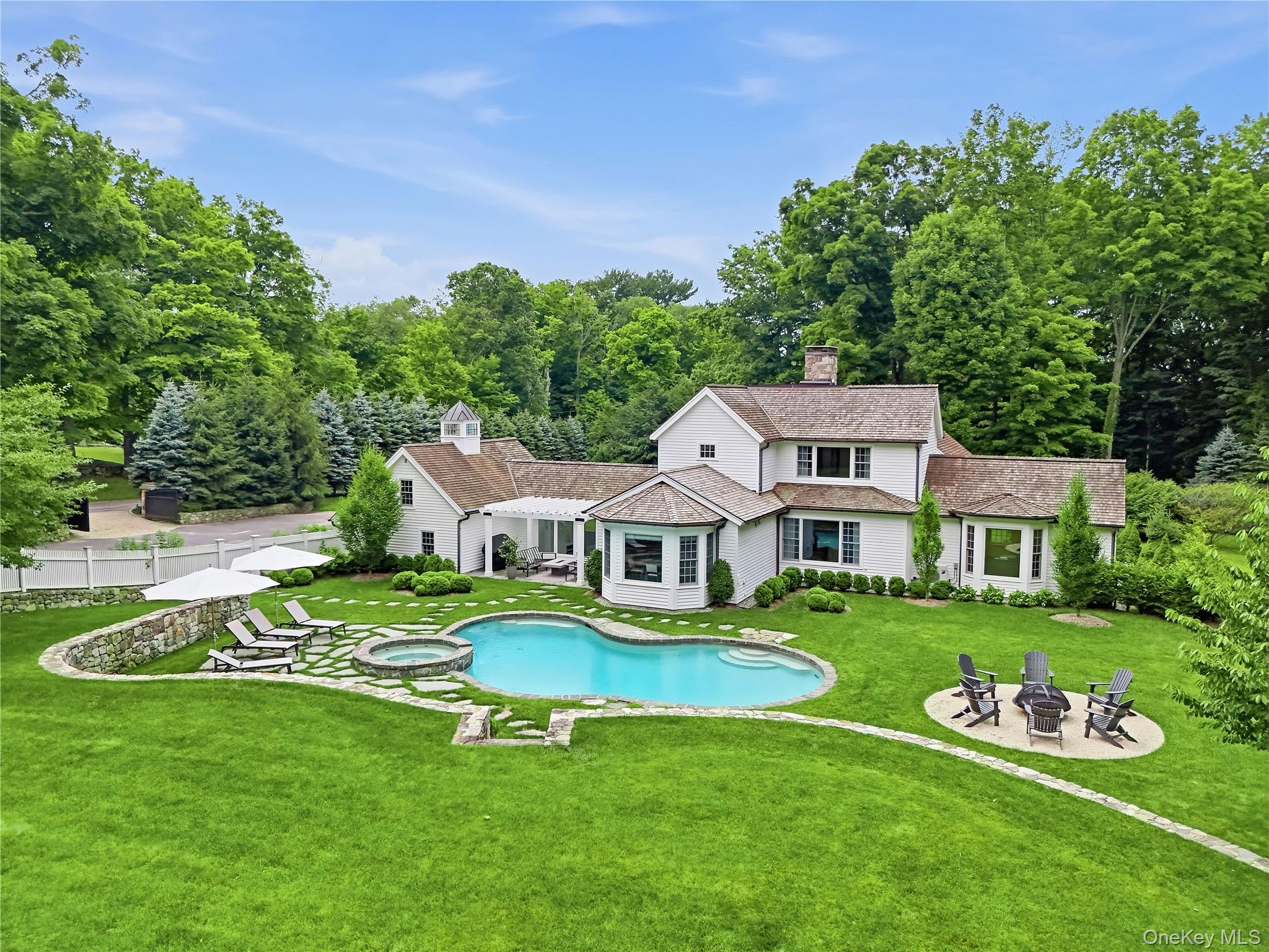 Beautifully renovated and impeccably maintained, this exceptional four-bedroom, four-bath residence is privately set behind gates on three picturesque acres in one of Westchester County’s most coveted communities. Thoughtfully redesigned with an emphasis on timeless elegance, modern comfort, and energy efficiency, the home features a state-of-the-art geothermal system, a stunning chef’s kitchen, and a resort-style heated pool and spa that create a seamless indoor-outdoor lifestyle.Extensive recent improvements include a complete kitchen expansion and renovation, an enhanced living room featuring a modern fireplace and expanded picture windows, a luxurious primary bath renovation, and the addition of a striking glass-enclosed mudroom entry. Every update has been carefully curated to elevate both form and function while maintaining the home's sophisticated character.The outdoor setting is equally impressive, with professionally designed landscaping, a newly established meadow, custom copper gutters, upgraded irrigation, extensive masonry enhancements, a stylish pergola, and perimeter deer and pool fencing. The result is a private, park-like retreat perfectly suited for both entertaining and everyday enjoyment.Offering exceptional privacy, turnkey condition, and a highly commutable location, this refined Pound Ridge estate embodies modern luxury living at its finest.