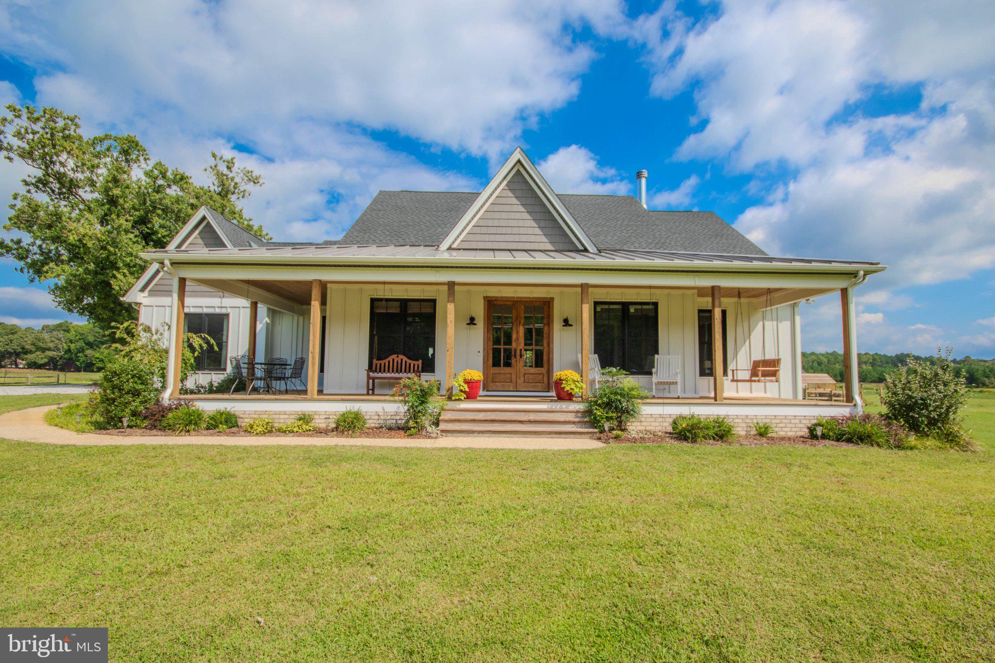 Beautiful custom-built one-story farmhouse, designed and built as the builder’s own personal home, set on 6.1 picturesque acres. Offering 2,457 square feet of thoughtfully designed living space, this exceptional property combines timeless farmhouse character with quality craftsmanship, abundant natural light, and modern amenities.The spacious open floor plan features a dramatic Great Room with cathedral ceiling, exposed wood beams, stone wood-burning fireplace, and two remotely operated skylights. The adjoining kitchen and dining area offer custom wood cabinetry, granite countertops, a large 4' x 9' center island, farmhouse sink, walk-in pantry, commercial gas range, and Bosch stainless steel appliances. Remote-operated skylights and wood beams continue throughout the kitchen and dining areas.The spacious primary suite features a cathedral ceiling, two skylights, custom walk-in closet, and luxurious bath with oversized soaking tub with granite surround and a 5' x 6' custom tiled walk-in shower with dual shower heads. Two additional bedrooms are located on the opposite side of the home and share a full bath. An office/library provides a dedicated workspace, while the family room features a 12-foot-wide wall of sliding doors opening to the rear patio, along with a wood ceiling and skylight.A versatile additional room with windows, sliding doors, and skylight currently serves as an art studio and opens directly to the patio. A convenient mudroom provides entry from the oversized attached 25.6' x 26' garage, which features two 8' garage doors, openers, insulation, drywall, and stair access to a fully sheathed 12' x 26' attic storage area complete with rooftop cupola and weathervane.Throughout the home are chestnut-tone wood laminate and plank flooring, custom woodwork, built-in bookcases and cabinetry, barn doors, recessed lighting, ceiling fans, and extensive interior and exterior fixtures. Large custom black aluminum-over-wood insulated windows with full screens provide exceptional natural light. The impressive 8-foot-high, 5'4"-wide pair of custom Adler wood front doors is stained to complement the flooring. A welcoming wraparound front porch features a wood ceiling and abundant electrical outlets.Exterior construction includes treated and prefinished LP SmartSide board-and-batten siding with Azek trim. The front porch is topped with a standing-seam metal roof, while the home and garage feature architectural shingles.Energy-efficient features include a Bryant extra-high-efficiency heat pump with dehumidifier, three thermostats zoning the home into three areas, encapsulated and conditioned crawl space with spray-foam insulation on exterior walls, 2x6 insulated exterior walls, and 16" spray-foam ceiling insulation. Additional features include Rinnai on-demand gas hot water, whole-house fire sprinkler protection, and an alarm system.The outdoor living spaces are equally impressive, with a 20' x 22' pebble-finished concrete patio, extensive landscaping, fishpond, wood-burning fire pit area, and a custom-built brick pizza oven with large dome and door.The property also offers an outstanding collection of outbuildings. A 28' x 36' fully electric garage/shop features two garage doors, six windows, concrete floor, 10'6" ceiling height, and an attached 11' x 36' carport. A separate 24' x 44' pole building offers metal siding and roof, 13' clear interior height, gravel floor, electric, and 12' sliding doors.The fenced 55' x 100' garden area includes a separate 25' x 50' dog play area, several fruit trees, a 12' x 16' garden shed, and an 8' x 12' custom greenhouse. A rare opportunity to own a meticulously crafted farmhouse with exceptional amenities, versatile outbuildings, and room to enjoy the best of country living.***Property listed below appraised value***