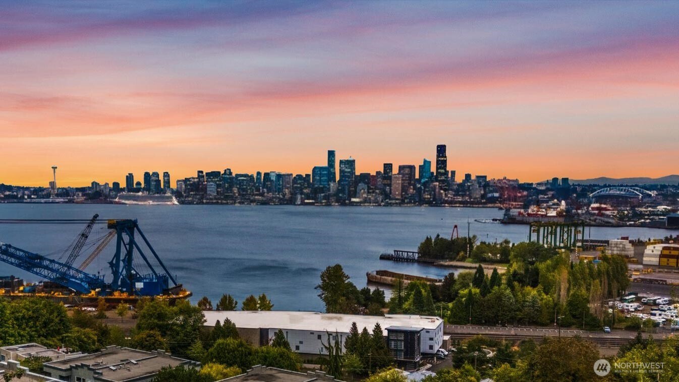 Enjoy spectacular views of Elliott Bay and the Seattle skyline from this beautifully remodeled two-bedroom condo. Step inside to new flooring that creates a clean, cohesive look throughout most of the home. The bonus room features high-end custom built-ins with an integrated desk, generous workspace, and shelving—ideal for a polished home office. A spacious guest bedroom offers an oversized closet, while the fully updated three-quarter bathroom includes a glass-enclosed shower and towel warmer. The open kitchen is equipped with a gas range, abundant counter and cabinet space, and a convenient pantry. Just off the kitchen, the formal dining room is perfectly positioned for entertaining guests. The expansive living room features a gas fireplace and opens to a balcony view, creating an effortless indoor-outdoor connection. The primary suite captures the home’s exceptional outlook, with eastern sunlight and sparkling city views to greet you each morning. Its beautifully updated bathroom offers a glass-enclosed shower, oversized jetted tub, double sinks, and a walk-in closet. New recessed lighting throughout the living areas adds a fresh, modern finish. New washer, dryer, hot water tank and garbage disposal. Coveted individual garage, additional assigned parking space, and ample guest parking provide convenience and flexibility. Set within a wonderful, gated community, this home offers a quick commute to downtown Seattle and easy access to fabulous Alki Beach. Welcome home!