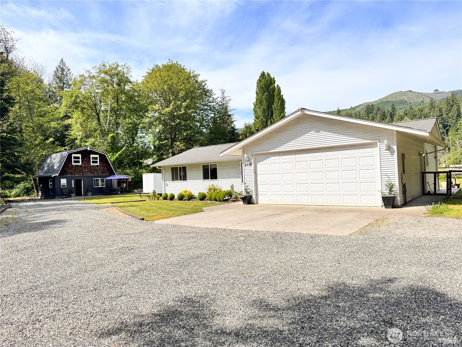 Welcome to your private, beautifully maintained Northwest retreat property surrounded by mountain views, towering evergreens, and peaceful outdoor living.    Set on a usable 0.74-acre lot with a fenced backyard. This move-in-ready 3-bedroom, 2-bath home offers comfortable single-level living with an open-concept layout filled with natural light and anchored by a warm wood-burning fireplace.    Outside is where this property truly shines. Enjoy mountain views, mature landscaping, a stamped concrete patio, a pergola seating area, a greenhouse, garden space, and a sports court ready for basketball, pickleball, gatherings, or future customization.    The detached, powered outbuilding with water offers exceptional flexibility for hobbies, guests, workspace, storage, home business use, or potential future ADU use (buyer to verify). A spacious 2-car garage, RV parking, and abundant off-street parking provide room for vehicles, trailers, toys, and entertaining.    Properties offering this combination of usable land, privacy, recreation, flexibility, and move-in-ready comfort are becoming increasingly difficult to find.    Located near schools, trails, rivers, and year-round recreation, this property strikes a balance between peaceful country living and everyday convenience that buyers are searching for.