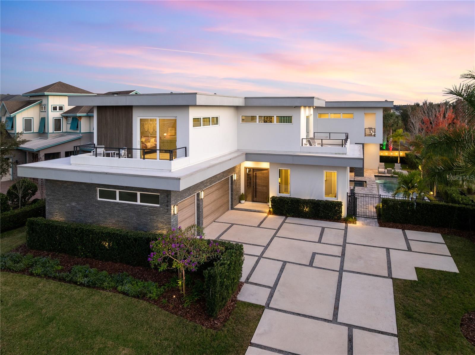 Stunning Custom Modern Estate with Lake Views in Laureate Park. Located on a premier corner cul de sac homesite in the heart of Laureate Park, this custom built modern estate offers nearly 4,500 square feet of refined living with sweeping lake views and unforgettable sunset skies. Clean architectural lines, soaring ceilings, custom tile work, and wide plank flooring create a dramatic first impression, while UV coated windows fill the home with natural light. The open main living areas are anchored by a chef’s kitchen featuring solid wood cabinetry, stone countertops, a hidden Sub Zero refrigerator, built in appliances, an oversized island, and a walk in pantry, ideal for both everyday living and entertaining. Designer chandeliers and lighting are featured throughout the home, along with custom imported European curtain rods that elevate every space.The first floor includes a private office that easily converts to a fifth bedroom, a guest en suite bedroom with full bath, and a dedicated pool bath offering exceptional flexibility. Oversized sliding doors open to an expansive covered lanai with wood paneled ceilings, recessed lighting, and ceiling fans. The private backyard is a true resort style retreat with a heated saltwater pool and spa, expansive paver decking, lush landscaping, tranquil lake views, and unparalleled sunset views. A fully equipped outdoor kitchen with built in grill, vent hood, stone counters, and bar seating completes the space and is enhanced by a whole yard app controlled Thermacell system.Upstairs, a spacious loft opens to a covered balcony overlooking the lake. The primary suite is a private sanctuary with its own balcony and a spa inspired bath featuring a freestanding soaking tub, glass enclosed walk in shower, dual floating vanities, and a custom walk in closet. A dedicated tankless water heater serves the primary suite and kitchen. Additional highlights include generously sized bedrooms with en suite options, Ecobee app controlled thermostats, a whole house water filtration system with drinkable water at every faucet, custom Lutron motorized shades with select blackout features, a professionally wired ceiling sound system, and an oversized three car garage with epoxy flooring.Enjoy the Laureate Park lifestyle with access to resort style pools, the Aquatic Center, LP Fit gym, parks, dog parks, and over 44 miles of trails. Centrally located in Lake Nona near Medical City, Nemours, the VA Hospital, dining, shopping, Orlando International Airport, USTA, and major highways.