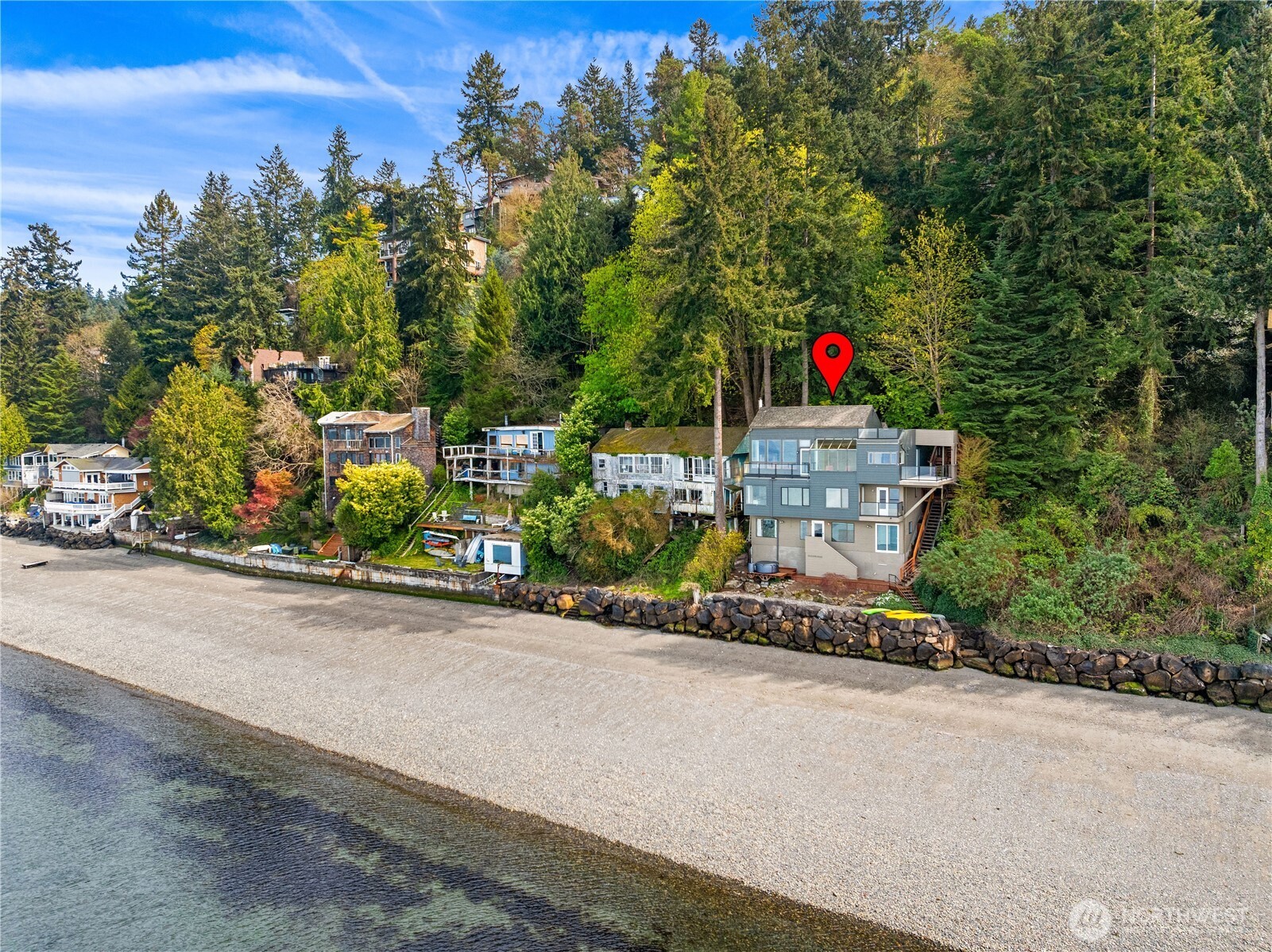 Welcome to Maplewild—An opportunity to own 60 feet of low-bank waterfront and enjoy true Pacific Northwest living. This inviting 4-bedroom, 2.25-bath home blends comfort, flexibility, and an unbeatable connection to the water. Imagine living in a peaceful, private setting that feels worlds away, yet remains conveniently close to the city. Inside, natural light fills the open living spaces, where large windows frame calming waterfront views. The layout is ideal for everyday living and entertaining, with seamless flow between the kitchen, dining, and living area. Four bedrooms offer versatility for guests, work-from-home needs, or extended living. Step outside and embrace the lifestyle. The gentle, low-bank shoreline provides easy access for kayaking, paddleboarding, beachcombing, or simply relaxing by the water. A 34' boat anchor and buoy adds the convenience of private moorage, making spontaneous boating and sunset cruises effortless. Unwind in your private hot tub, perfectly positioned to take in the surrounding serenity, an ideal spot to relax under the stars after a day on the water. Above it all, the rooftop deck offers sweeping panoramic views, creating an incredible space for entertaining or quiet reflection. Maplewild is more than a home; it’s a secluded waterfront retreat where privacy, comfort, and natural beauty come together.