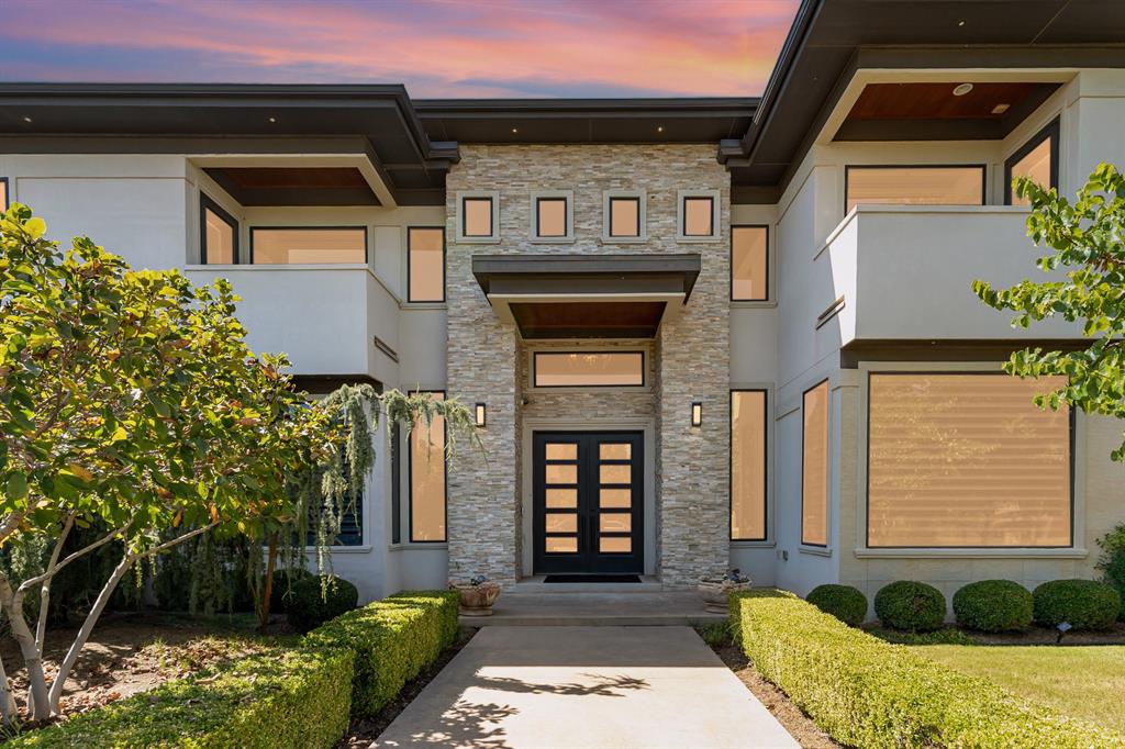 Experience unparalleled elegance in this 6400 sqft custom-built estate in exclusive Carrington Lakes. Surrounded by serene, tree-lined beauty, this home showcases exceptional craftsmanship and luxurious details. The grand entryway boasts honey onyx columns, travertine floors, and soaring ceilings, leading to one of four living rooms with a massive picture window overlooking the backyard patio. A maple staircase with black marble accents adds to the grandeur. The main living room features oversized windows framing the pool, waterfall, and marble fire pit. Double-glazed windows provide stunning views, energy efficiency, and soundproofing. 4 Zoned  A/C/Heat and Tankless Water Heater, ventless fireplace and entertainment area enhance the space, which flows into the gourmet kitchen with an Italian farmhouse sink, black granite countertops, custom cabinetry, and top-tier KitchenAid appliances. A walk-in pantry and butler’s pantry connect to the formal dining room with cove lighting and a modern tassel  chandelier. An adjacent garden patio offers tranquil views of the park and lake. The main-floor primary suite is a luxurious retreat with a gold crystal chandelier, honey onyx en suite, dual walk-in closets (one an air-conditioned safe room), a jetted tub, and rain shower. A custom library/office with built-in shelving and a granite fireplace completes the main floor. Upstairs, two living areas offer entertainment and relaxation. The first includes a full kitchen, honey onyx backsplash, and access to a balcony with park and lake views. The second opens to the grand balcony overlooking the backyard and lake. The Brother and Sister suites each offer private baths, walk-in closets, and balconies, with the Brother Suite spacious enough for a sitting area. A theater room doubles as a bedroom, while a fifth bedroom offers versatility as an office, gym, or storage. Featuring marble exterior walls, and insulated 4-car garage includes built-in storage. Schedule a private showing!