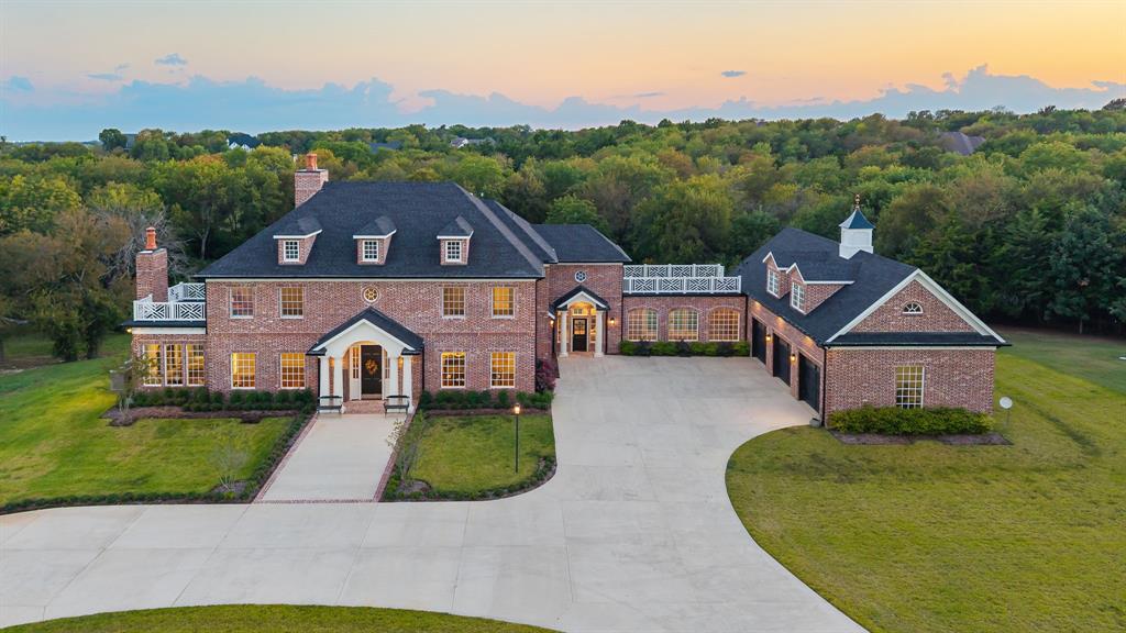 Step into timeless elegance with this one-of-a-kind Georgian Colonial estate, masterfully designed with craftsmanship and sophistication at every turn. Nestled on a serene, tree-lined 2-acre lot, this custom home welcomes you with a grand circle drive and stunning curb appeal, setting the tone for the refined luxury within.  Inside, you’ll find rich custom woodwork, exposed brick accents, and an abundance of natural light that fills every room. The chef’s kitchen is a culinary dream, featuring a massive prep island, top-tier appliances, and a walk-in appliance pantry designed for both beauty and functionality. Enjoy morning coffee in the sun-drenched solarium, or unwind with a good book in the private home library. The expansive executive office offers an inspiring setting for the most discerning professional—ideal for hosting meetings or managing business affairs in style.An in-home elevator provides effortless access to every level, including spacious attic storage. Step outside to experience multiple patios and balconies overlooking the peaceful, wooded estate—perfect for entertaining or quiet reflection. A brick-laid breezeway connects to the oversized three-car garage, completing this remarkable property that seamlessly combines grandeur and comfort. This home is truly a rare find—a timeless statement of design, privacy, and luxury living in the heart of McKinney. Versa lift in garage; attic above garage is unfinished bonus room 48x13; elevator to second floor and attic on third floor; brick floors; Documents listing the many features can be found in Transaction Desk; double lot allows for addition of a pool house with guest quarters but not a second residence.