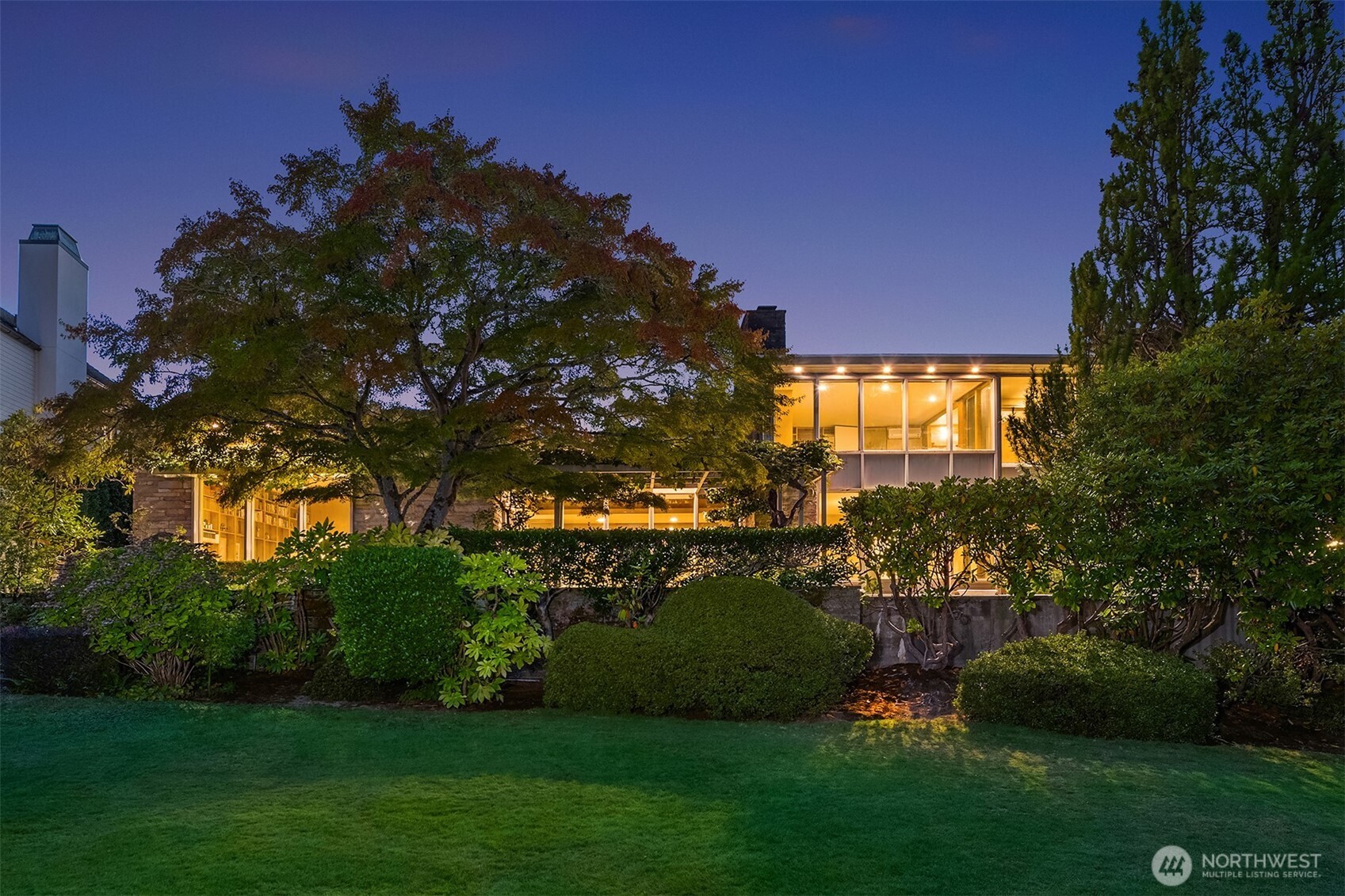 Tucked along one of Broadmoor’s most coveted streets, this grand mid-century home is a rare glimpse into an era when architecture was designed to bring people, light, and landscape together. Lovingly maintained by the same family for decades, the home retains an unmistakable sense of place—thoughtful proportions, warm original details, and expansive glass that invites the outdoors in.  At the heart of the home, a dramatic two-story living room rises beneath a wall of windows, framing views across the Broadmoor golf course and capturing the soft easterly light. It is a space made for lingering: morning coffee overlooking the fairways, long dinners with friends, or quiet evenings as the landscape changes beyond the glass.  The den offers a more intimate expression of mid-century design, with a sunken conversation area centered around a fireplace and surrounded by built-in bookshelves. Outside, the pool, private entry courtyard, and generous grounds create a private setting for summer afternoons and easy entertaining.  With a two-car garage, a peaceful residential setting, and Madison Park a short distance away, the location is as effortless as the architecture is distinctive. A home with soul, history, and an enduring connection to its surroundings—ready for its next chapter.
