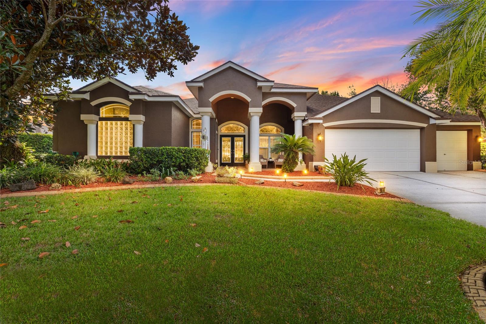 A showstopping pool home where commanding architecture, dramatic interiors and resort-style outdoor living come together on half an acre in Lutz. This original-owner Avalon Builders residence offers 4 bedrooms+office and bonus room, 3 baths and 3,175 sq ft of single-story living in a gated community. Major improvements include a 2020 roof, newer water heater and three separate, fully PAID off solar systems serving the home, pool and attic fan. A columned portico, tropical landscaping and landscape lighting create a striking arrival. Decorative double glass-entry doors open to an elegant foyer with graceful arches, architectural columns and plantation shutters. Double French doors lead to a private office. The home flows into impressive formal living and dining rooms with soaring ceilings, elegant details and beautiful pool views. The living room showcases a multi-tier tray ceiling with crown molding, decorative niches and expansive sliders framing the screened lanai. The adjoining dining room features a large arched window, plantation shutters and decorative lighting, creating a light-filled introduction connected to the outdoors. The heart of the home unfolds into an impressive open kitchen, café dining area and family room designed for gathering. The kitchen features Quartz countertops, decorative tile backsplash, 42-inch cabinetry with crown molding and glass-front displays, under-cabinet lighting and an angled breakfast bar. GE Café appliances include a Precision cooktop, microwave and double wall ovens, complemented by a Samsung French-door refrigerator and walk-in pantry. The window-filled café overlooks the salt water pool w/ spa and offers direct lanai access. The family room features a soaring vaulted ceiling, marble fireplace and expansive sliders opening the living space to the pool and lanai. Privately positioned, the primary suite is a spacious retreat with a tray ceiling, crown molding, pool views and sliders to the lanai. A private hallway provides two walk-in closets plus a linen closet. The primary bath offers separate vanities, makeup space, private water closet with bidet, soaking tub with glass-block backdrop and a tiled walk-in shower with Listello detailing. Three additional bedrooms complete the sleeping spaces. A spacious bonus/game room adds exceptional flexibility with a double sided wood burning fireplace, French doors and sliders overlooking and opening to the pool and lanai. The laundry room includes a utility sink, workspace, cabinetry and washer/dryer. Outdoors, the Florida lifestyle takes center stage. The expansive screened lanai surrounds a free-form pool with brick pavers and multiple covered and open-air seating areas; the hot tub remains. A spectacular screened outdoor kitchen and entertaining pavilion features a rich wood-plank ceiling, recessed and pendant lighting, ceiling fans, extensive cabinetry, stone countertops, breakfast-bar seating, stainless cooking equipment, sink, ice maker, beverage refrigerator and a stone gas fireplace. Beyond the screened entertaining spaces are a spacious lawn, multiple varieties of fruit trees and private putting green with new turf. The partially fenced yard includes exterior walk-in storage. Features include epoxy garage flooring and side-yard access. With exceptional indoor-outdoor flow, dramatic architectural character and a resort-style feel, this distinctive gated-community residence is designed for memorable entertaining and the Florida lifestyle.
