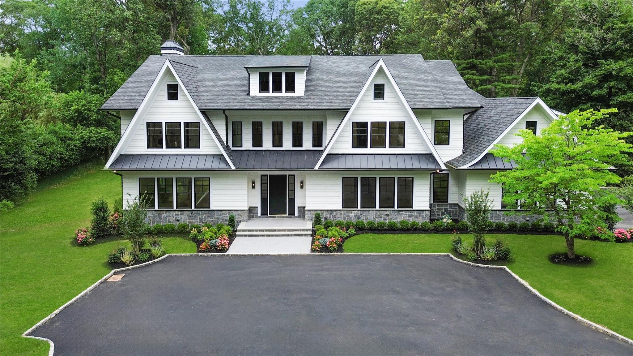 Brookville | 63 Fruitledge Road offers an unparalleled lifestyle of luxury on Long Island's Gold Coast. This newly completed home features a sleek, modern colonial exterior, with countless, black-encased windows allowing natural light to flood the entire interior. Upon entering, the soaring foyer welcomes you with open space and two convenient coat closets and beautiful powder room with pristine marble details. The formal living room features a custom wet bar with wine fridge, ideal for entertaining year-round. An impressive, open-concept den is lined with a wall of floor-to-ceiling windows providing a view of the expansive backyard, with a marble-encased fireplace to bring a cozy feeling on colder days. An impeccably-designed, fully custom kitchen serves as the heart of the home, centered around the large, waterfall island, with custom cabinetry and paneled appliances - including two Gaggenau wall ovens, two Bosch dishwashers, and SUBZERO refrigerator and freezer. Off the kitchen is an open butler's pantry that leads to a formal dining room.

Tucked behind the kitchen and dining area is an open mudroom space with full bathroom, catering to not only the back patio, but the 3-car garage and side entrance as well. Additionally, this service area offers a first floor bedroom, large pantry, and back staircase leading both upstairs, and to the expansive basement - also featuring an entrance off the side courtyard. 

Upstairs, the oversized primary suite is hidden behind double doors that open to high ceilings, and picture windows with views of the beautiful backyard. Two walk-in closets with built-ins offer plenty of organization options, while the 
en-suite full bathroom includes soaking tub, separate vanities, makeup vanity, wash room and full steam shower. The additional four bedrooms all feature their own en-suite full bathroom and walk-in closet. A large laundry room sits at the end of the hall, with ease of access to back staircase and linen closet. 

Outside, a breathtaking Gunite 40' x 20' saltwater & heated pool takes center stage, with pavers leading from the outdoor kitchen and patio. The impeccable combination of craftsmanship and design come together at 63 Fruitledge Road - a modern take on the timeless Brookville lifestyle.