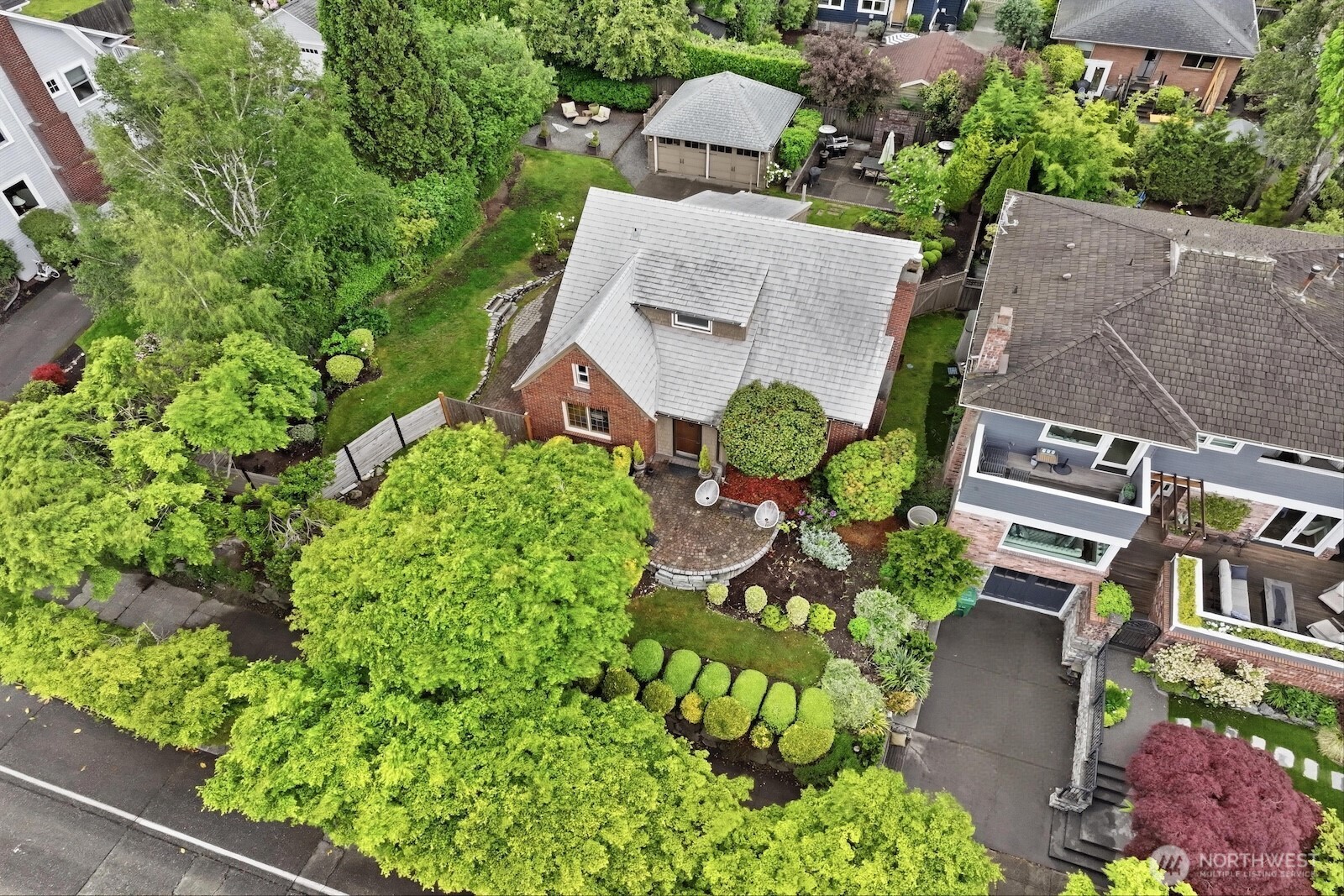 Character, charm & flair, sited on a larger-than-average lot in sought-after Magnolia: this classic 1920's brick Tudor is a must-see! Modernized for 21st century living but all the unique & desirable details from the home's original era intact, including coved ceilings, hardwood floors, built-in shelves, a centerpiece fireplace & period lighting fixtures - all built w/ impressive craftsmanship & style. Watch cruise ships, ferries & even orcas in Elliott Bay through windows in multiple rooms, or relax on the inviting front paver patio to take in gorgeous sunset colors & your quiet, idyllic neighborhood. A newly opened-up kitchen acts as the anchor for quiet nights in or get-togethers of any size, seamlessly flowing outside to a sprawling patio w/ a built-in fireplace, lush greenery & plenty of room for grilling & dining al fresco. Fantastic layout w/ versatility galore: 1 bed on the main, 2 upstairs, + a huge rec room, bonus room, 4th bed, chic 3/4 bath & oversized laundry rm on the lower level (with great potential for an ADU). Mature wisteria, hydrangea, ferns & other plantings create a private backyard oasis you'll love to relax, play & entertain in. The detached garage + long driveway offer space for multiple cars & hobbies. Tucked on a quiet street w/ unbeatable proximity to Magnolia Village, top-rated schools, the Magnolia Bridge & all the perks of urban living + downtown just mins away.