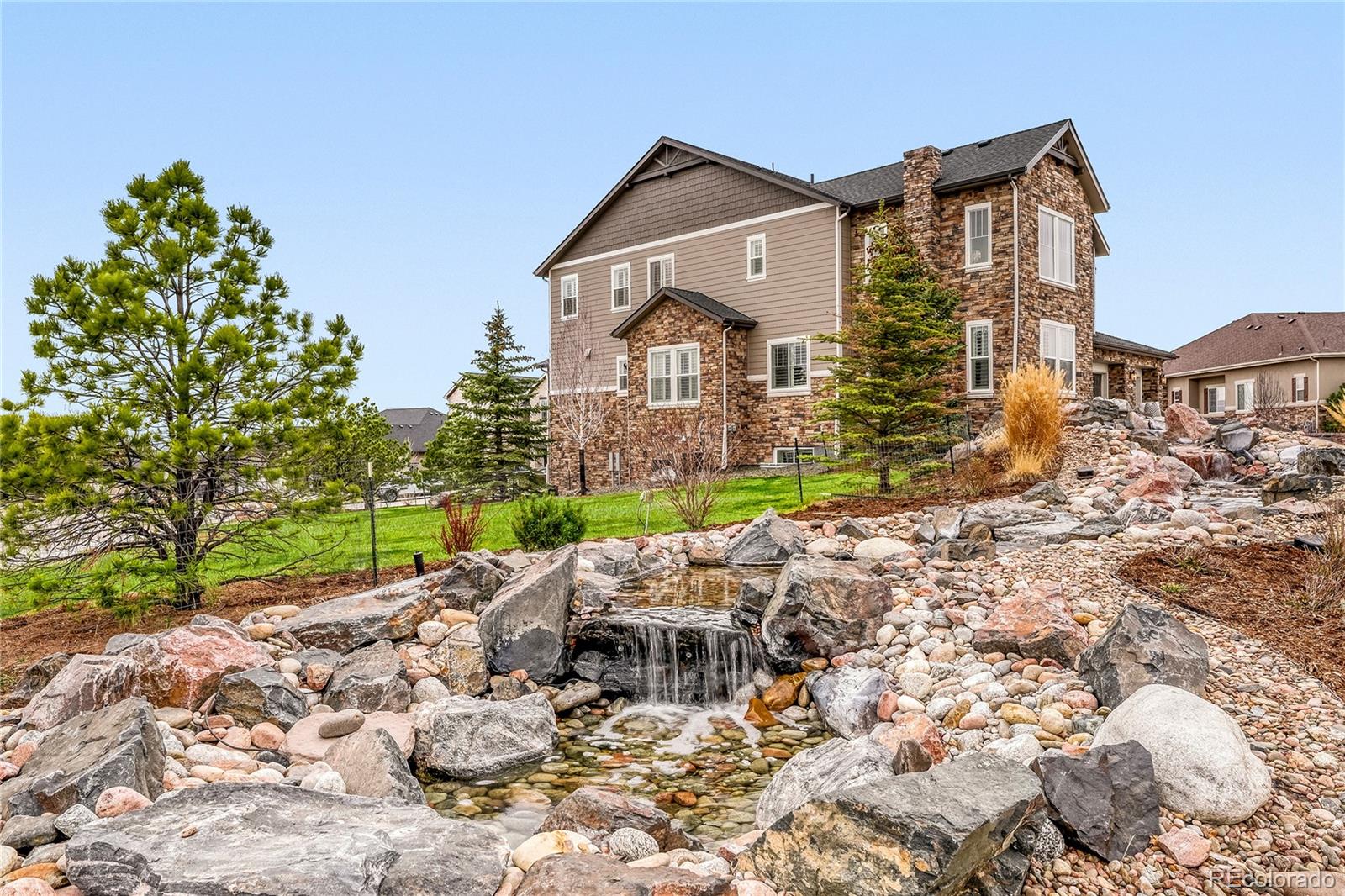 Luxury Home in the Prestigious Timbers Pinery Neighborhood in Parker Colorado. A very rare offering of one of the largest floorplans featuring 7,440 sq. ft. of living space. The home has been Professionally Designed, it is remarkable and stunning and has every imaginable amenity and upgrade. Every design and detail has been carefully considered to achieve the perfect balance of style, elegance and comfort. The home impresses with beautiful pine trees centered around a waterfall. The Home has 6 bedrooms (one is on the main level with en-suite bath) and 6 bathrooms, private office, and a finished basement. The inviting courtyard welcomes you inside to a beautiful foyer with 20 foot ceilings and a grand chandelier and designer lighting. Natural light fills the open-concept main level with soaring two story ceilings and expansive windows framing the living room centered on a gas fireplace with custom tile to the ceiling. As you proceed through the main floor you enter the designer kitchen crafted for everyday living and entertaining. Have breakfast and lookout to Pikes Peak. Custom cabinetry stacked to the ceiling with smart pull-outs, tile backsplash, quartz counters, chefs appliances create a a space both functional and beautiful. Just off the kitchen is a large family room with a fireplace with a stacking window slider that leads to the covered patio with mountain views. The kitchen flows into the dining area and living room, mudroom, laundry room and powder bath. Upstairs, the primary suite has beautiful mountain views and is a retreat with a double sided fireplace with custom tile to the ceiling and a large serenity seating area. The spa inspired bath includes a free standing soaking tub. Three additional bedrooms complete the upper level, offering ample space for family and guests. A Giant finished basement includes a bedroom, bathroom, large storage areas, a home theatre, an expansive area for family activities. Large basketball court and  large three car garage.