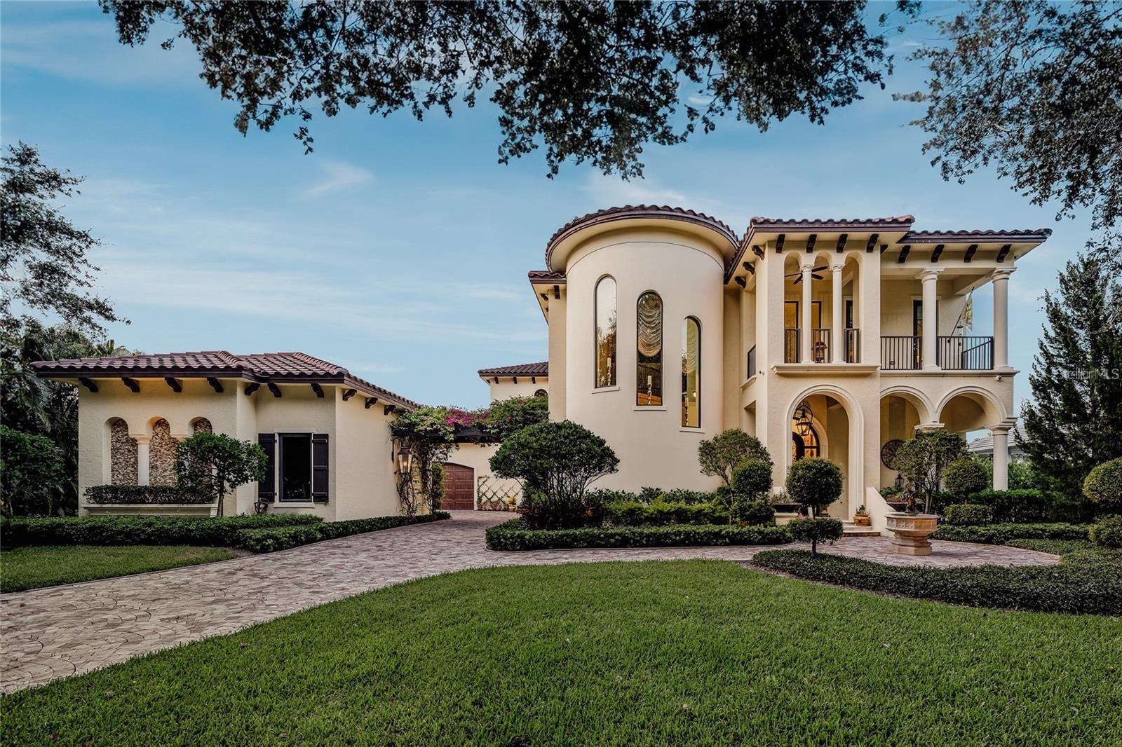 As you follow the canopied tree-lined streets, you will be welcomed to this Mediterranean-inspired custom waterfront home, masterfully constructed by the coveted P B Built builders. From the moment you arrive, you will be captivated by this architectural masterpiece, featuring a marble driveway flanked by New Orleans-style gas lanterns, a charming fountain, and a pergola adorned with vibrant bougainvillea. The elegant wrought-iron door invites you into a stunning foyer where dramatic ceilings and three arched windows guide your gaze to a magnificent spiral staircase. This staircase ascends to a circular dome ceiling, painted to resemble a serene marble and cloud sky, creating an awe-inspiring ambiance. The formal living room, with its hardwood floors, showcases six stately marble columns adjacent to a 300-bottle, climate-controlled wine cellar. This exquisite cellar features a barrel table, rustic walls, and warm lighting, designed to store a significant collection. Every element of this home is finely crafted with meticulous attention to detail. The casual family room boasts a full built-in wet bar and beverage center, overlooking an elaborate marble floor-to-ceiling gas fireplace with a floral design. This indoor-outdoor area seamlessly opens to expansive waterfront views of the serene, clear waters of the Loxahatchee River. The chef’s kitchen is equipped with stunning Fieldstone designer linen cabinetry with glass fronts, a serving island with exotic Volga Blue Granite wrapped around a copper sink imported from Mexico. A Wolf six-burner gas range with solid stone accents and rustic wood from a barn is complemented by a hand-painted tiled backsplash reflecting an Italian coastal village. Take your private elevator to the second floor, where you will discover the palatial owner's retreat, adorned with crown molding that accents powder blue tones. This luxurious suite includes an enormous walk-in closet, a marble fireplace that opens to a veranda with spectacular views. The sumptuous bath features two massive vanities, a walk-in shower lined with exotic tiles, and a relaxing jetted tub with its own fireplace. Each secondary bedroom is spacious, and the bathrooms are artfully designed. Step onto the terrace, where classical columns, electric screens, a cozy fireplace, and a fire bowl create a perfect gathering place to watch stunning sunsets. The disappearing edge pool with a swim-up bar and unique curving design blends seamlessly with the surrounding lush greenery, adding to the serene private ambiance. This is an entertainer's delight, complete with a sunken summer kitchen. For the boating enthusiast, a private dock, a forty-foot boat slip, and a floating dock provide ample space for watercraft. This riverfront oasis offers access to canoeing, kayaking, or simply enjoying the nature trails for utter peace. This one-of-a-kind gem has so many unique facets and intricate details that you must see to truly appreciate. For nature enthusiasts, nearby activities include the Jupiter Inlet Lighthouse, Busch Wildlife Sanctuary, beautiful beaches, easy nature trails, and Jonathan Dickinson State Park. Experience the ultimate blend of luxury and nature in this Mediterranean-inspired waterfront masterpiece. Schedule your private tour today and discover the unparalleled elegance and serenity that awaits.