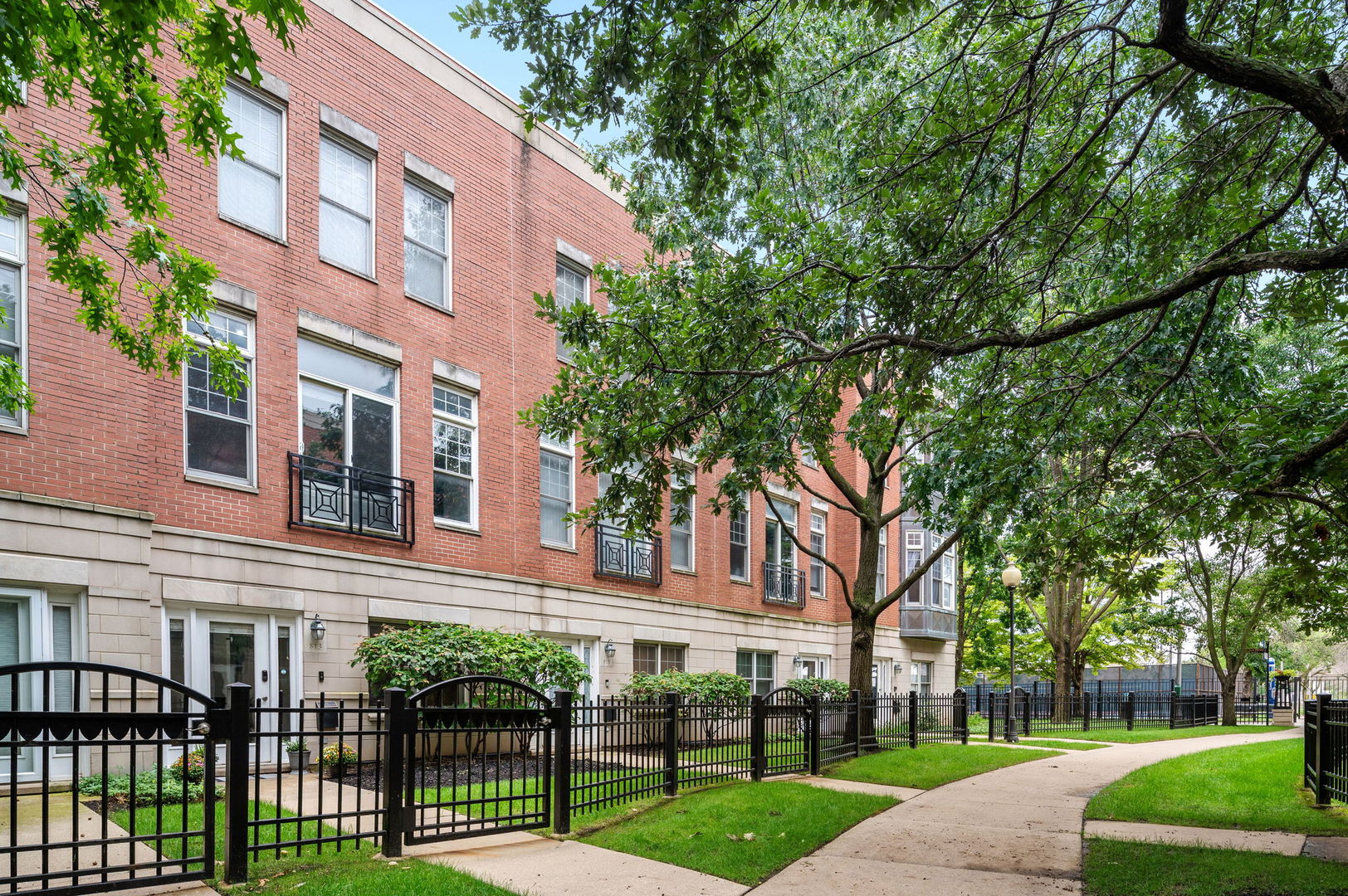 Nestled away in University Village, just off of Halsted Street, on a leafy and secluded pedestrian-only walkway, is this spacious 2BR + Den/Office, 2.1BA, red brick townhome with four levels of living space. Step through the front door and into a welcoming foyer that opens to a Den/Office with a gorgeous custom walnut built-in desk and bookcases, and could be enclosed to create a 3rd bedroom! The open concept main level on the second floor is filled with natural light (thanks to the unobstructed south view!) and hardwood floors throughout. The living room features a gas fireplace with adjacent shelving nooks, and plenty of space for a dining table and chairs and bar stool seating at the kitchen peninsula. This kitchen is well equipped with stainless steel appliances, granite countertops, newer backsplash, and a center island for meal prep and entertaining, plus a balcony with a gas hook-up for a grill. Unlike many townhomes, this one features a rare powder room on the main level! Upstairs are two spacious bedrooms with newer carpeting and fresh paint, and two baths. The primary suite comfortably fits a king size bedroom set, has a wall of closets with custom organizers, and a great en suite bath with double vanity, dual shower heads, and a linen closet. Perched on the top floor is the dog house with extra storage, leading to the private roof space with gorgeous skyline views. Own this home with the peace of mind knowing the furnace, AC and water heater have all been replaced within the last 3 years. Not to mention, this home has an attached 2 car garage! The location here offers exceptional urban living. Transportation is made easy with Halsted CTA buses right outside the door, Metra, and quick interstate access. Convenient and walkable, the area has multiple coffee shops, restaurants, parks, playgrounds and pet areas surrounding it. Enjoy some of the best dining round the corner on Maxwell and Taylor Streets. Vibrant energy with The University of Illinois Chicago campus at the foot of this complex. Close proximity to everything the West Loop, Little Italy, Pilsen, and Greektown have to offer!