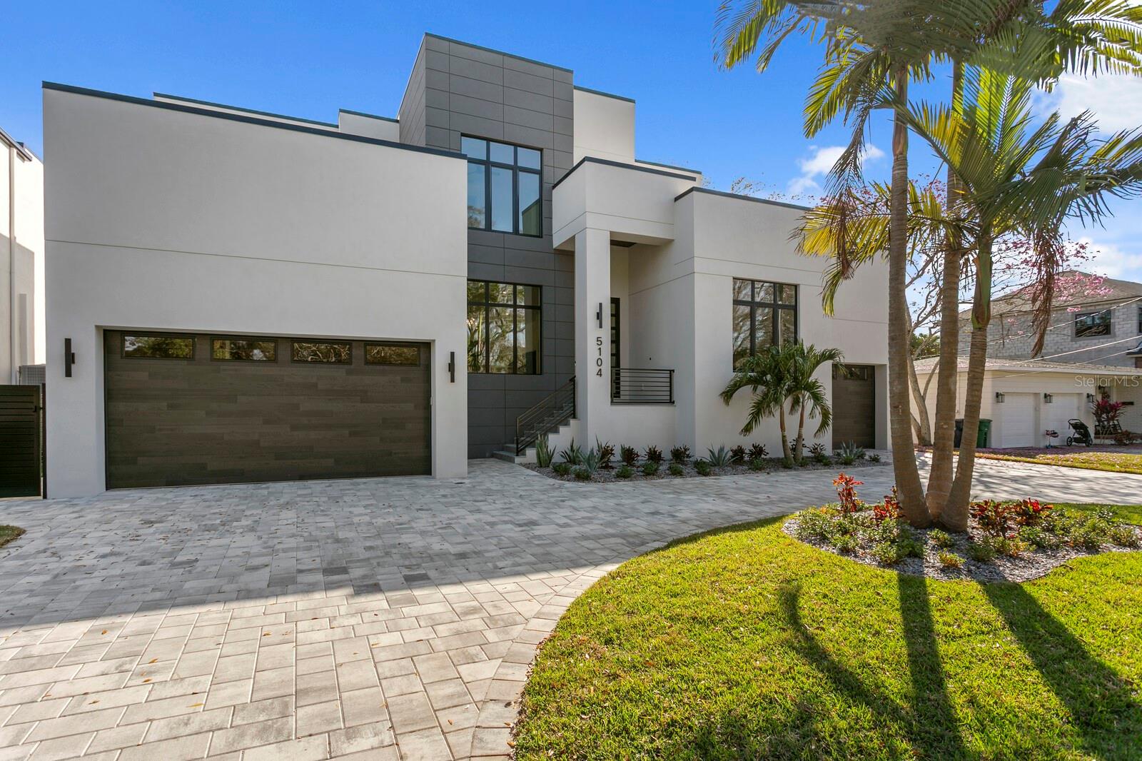 Under contract-accepting backup offers. Just completed and move-in ready, 5104 W Platt Street represents one of only ten residences currently available within the active Crescent Homes portfolio. Located in Tampa’s Beach Park neighborhood, this modern contemporary home is built with the same construction methods, engineering standards, and design execution found in Crescent Homes’ luxury custom waterfront estates, offering immediate availability while most new Crescent Homes deliveries extend into 2026 and 2027.The residence offers five bedrooms, four full baths, and one half bath across 4,521 square feet of heated living space and 6,264 total square feet under roof. Constructed with concrete block-on-block masonry, an engineered stem wall foundation, raised elevation, and hurricane-rated impact windows and doors, the home is designed for long-term structural performance and resilience in Florida’s coastal environment. Interior living spaces emphasize clean architectural lines and functional flow, featuring 10–12-foot ceilings, engineered hardwood flooring, level-5 smooth drywall finishes, LED lighting, and integrated smart home capability. The floor plan connects the kitchen, dining, and great room seamlessly to covered outdoor living areas, creating continuous indoor-outdoor living consistent with Crescent Homes’ current design approach.  The kitchen is equipped with Sub-Zero refrigeration, a Wolf dual-fuel gas range, microwave drawer, beverage refrigeration, solid surface countertops, and a walk-in pantry, with direct access to the outdoor kitchen and lanai for entertaining. Outdoor spaces include a covered lanai, fully equipped outdoor kitchen, and elevated pool and spa with automation system. A first-floor VIP guest suite and dedicated study or fifth bedroom provide flexibility for guests or remote work, while the second level accommodates the primary suite, additional bedrooms, bonus living space, and upstairs laundry as designed within the home’s architectural layout.  The primary suite is finished with dual walk-in closets and a spa-style bath featuring a freestanding soaking tub, frameless glass shower, and dual vanities.Forward-thinking construction elements include a built elevator shaft ready for future installation, 400-amp electrical service, EV charger pre-wire, epoxy-finished three-car garage with high-lift capability, tankless gas water heaters, foam insulation, fresh air intake system, pre-wiring for security, audio, and shading systems, and an engineered underground drainage system designed specifically for Florida weather conditions. Positioned minutes from Tampa International Airport, Westshore business district, dining, and Gulf beaches, this completed Crescent Homes residence delivers immediate ownership of a finished product within a limited builder portfolio—without construction timelines or uncertainty.