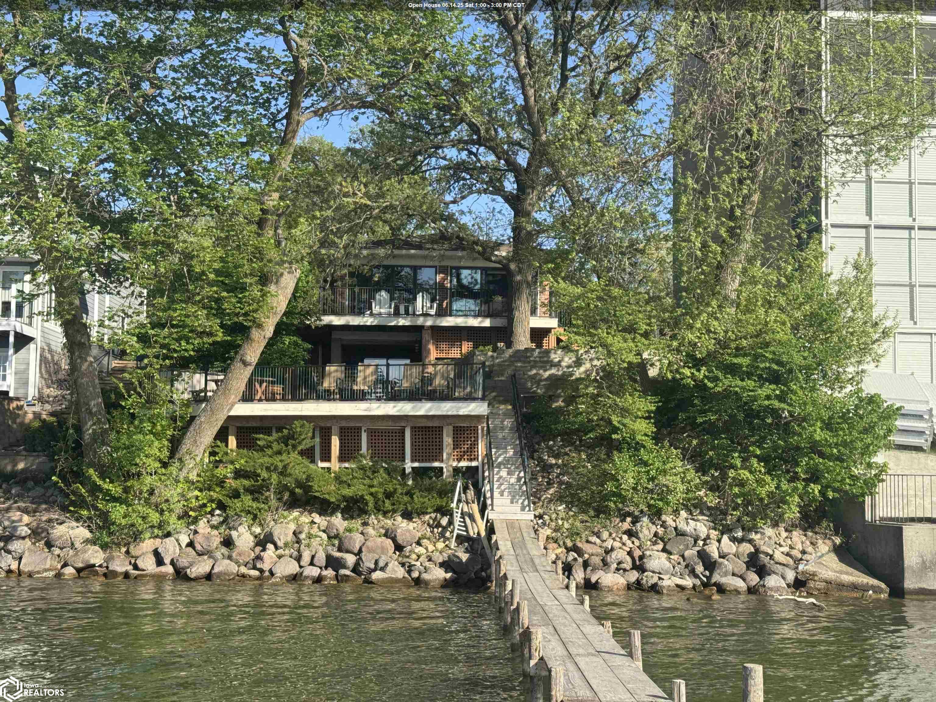 Set along 70 feet of stunning shoreline, this brick and cedar lake home offers comfort, style, and year-round enjoyment. With breathtaking lake views and impeccable attention to detail, it’s the perfect retreat for all seasons. Step through sliding glass doors to the expansive main deck, now featuring updated railings for unobstructed panoramic views. Three lakeside decks provide multiple spaces to relax and entertain, while a flagstone patio framed by limestone retaining walls adds to the outdoor charm. A small pond enhances the landscape, and the included dock makes lakefront living effortless and enjoyable.  Inside, the kitchen boasts Cambria quartz counters, crown molding, and stunning lake views. Hardwood floors and abundant natural light from Pella windows enhance the warmth of this inviting space. The walkout lower-level family room features Knotty Pine walls, a built-in bar with storage, a beverage refrigerator, and an additional bedroom and bath—ideal for guests. An oversized heated garage provides ample storage. Additional features include a washer and dryer, plus all window treatments.