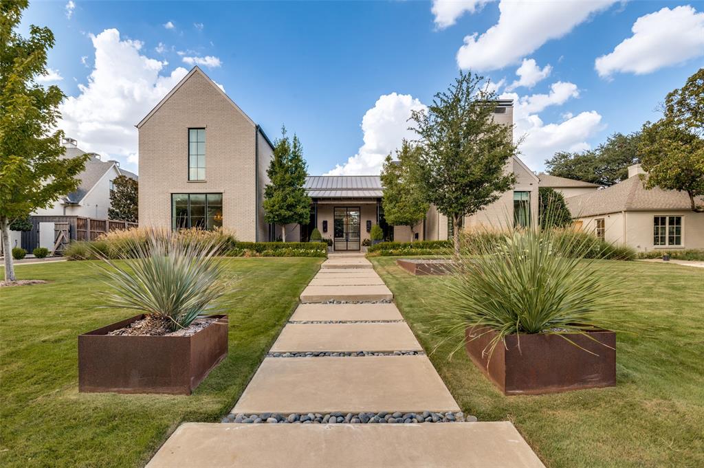 Architectural details, exceptional natural light and thoughtfully selected finishes define this striking Dallas home. With contemporary farmhouse influence, the steel-and-glass entry, soaring windows, warm hardwood floors and architectural details create a home that feels sophisticated, inviting, and thoughtfully composed. The main living space is open and welcoming, with custom built-ins, fireplace, statement lighting and floor-to-ceiling custom window coverings.The kitchen flows naturally into the living area with an oversized island, extensive cabinetry, quartz countertops, stainless appliances, geometric tile and distinctive metal vent hood. Nearby, the dining room includes built-in cabinetry and a beverage refrigerator, while a fifth bedroom can also function beautifully as a private study.The primary suite features vaulted ceilings with oak beams, tall windows overlooking the backyard, a spa-inspired bath and custom closet. Upstairs, a guest suite is complemented by a private sitting room or flex space, while two additional bedrooms each offer full baths. A spacious family or media room with abundant cabinetry creates another inviting place to gather.Outside, the oversized lot offers a remarkably private setting surrounded by mature trees and landscaping, with generous lawn space around the pool. The pool features an in-floor cleaning and circulation system for simplified maintenance, while the covered patio includes a fireplace, TV area and custom built-in grill with extraction fan. Smart Lutron lighting throughout the downstairs, exterior front and sides, custom window treatments, two tankless water heaters, a gated driveway and three-car garage complete the home.