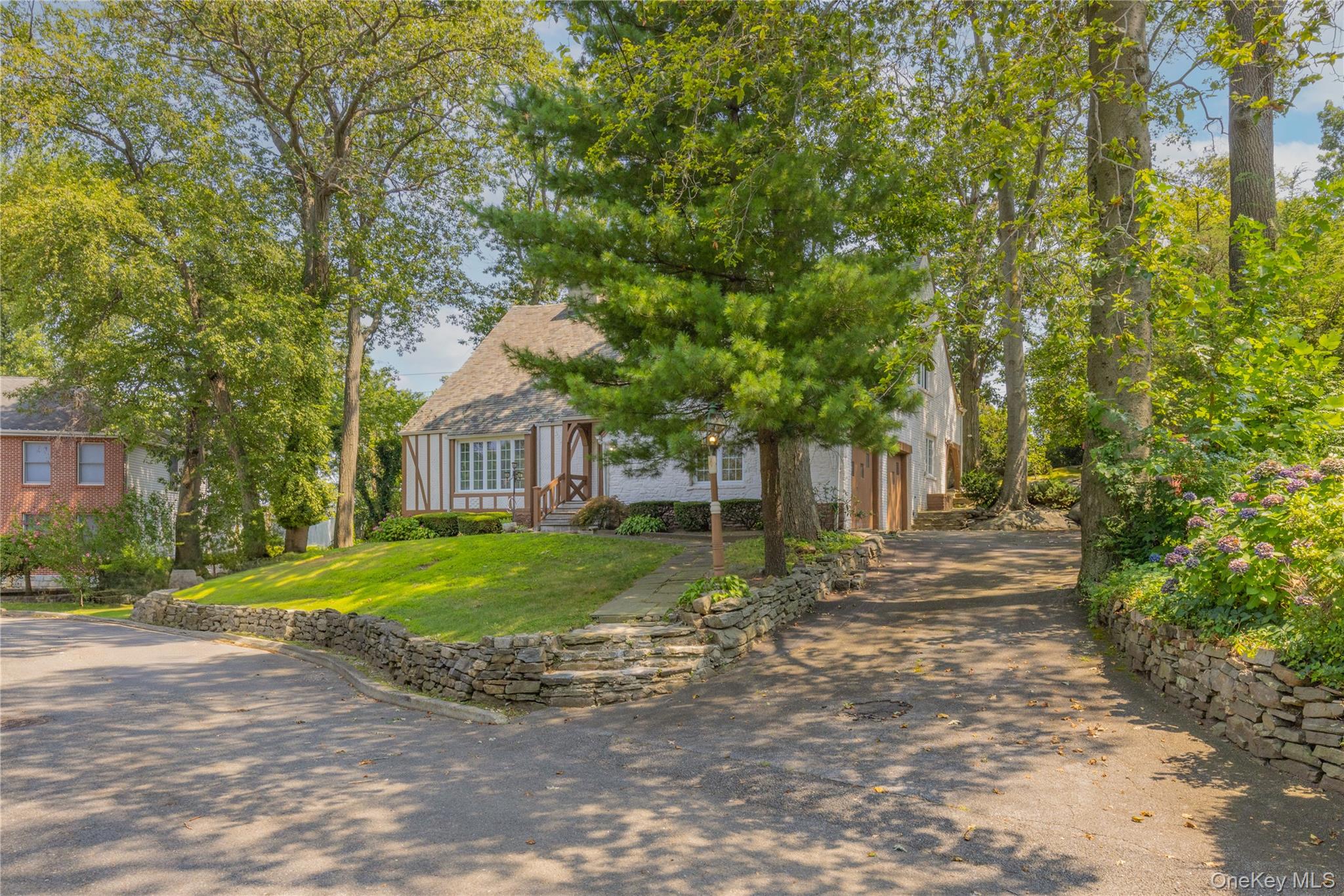 Charm, charm and more charm! A wonderful Tudor style chalet, right out of a storybook and loaded with curb appeal. Add to that, it's located right in the heart of the quiet neighborhood of Bryn Mawr Knolls, set on a private 1/4 acre grassy knoll. You'll fall in love with the vaulted ceiling step-down living room lined with the original built-in oak bookshelves. Formal dining room w/built-in corner cabinet and walk-out to patio. MEIK. Second floor has a sprawling layout that maximizes privacy with a large corner bedroom/2 closets, large full bath, another bedroom and a master suite with en-suite bath and finished generous finished storage room. Up a half flight of stairs is the 4th bedroom with en-suite bath and attached office. Laundry and mechanicals in the lower level. Attached two car garage. Just 1.5 miles to Bronxville Village.