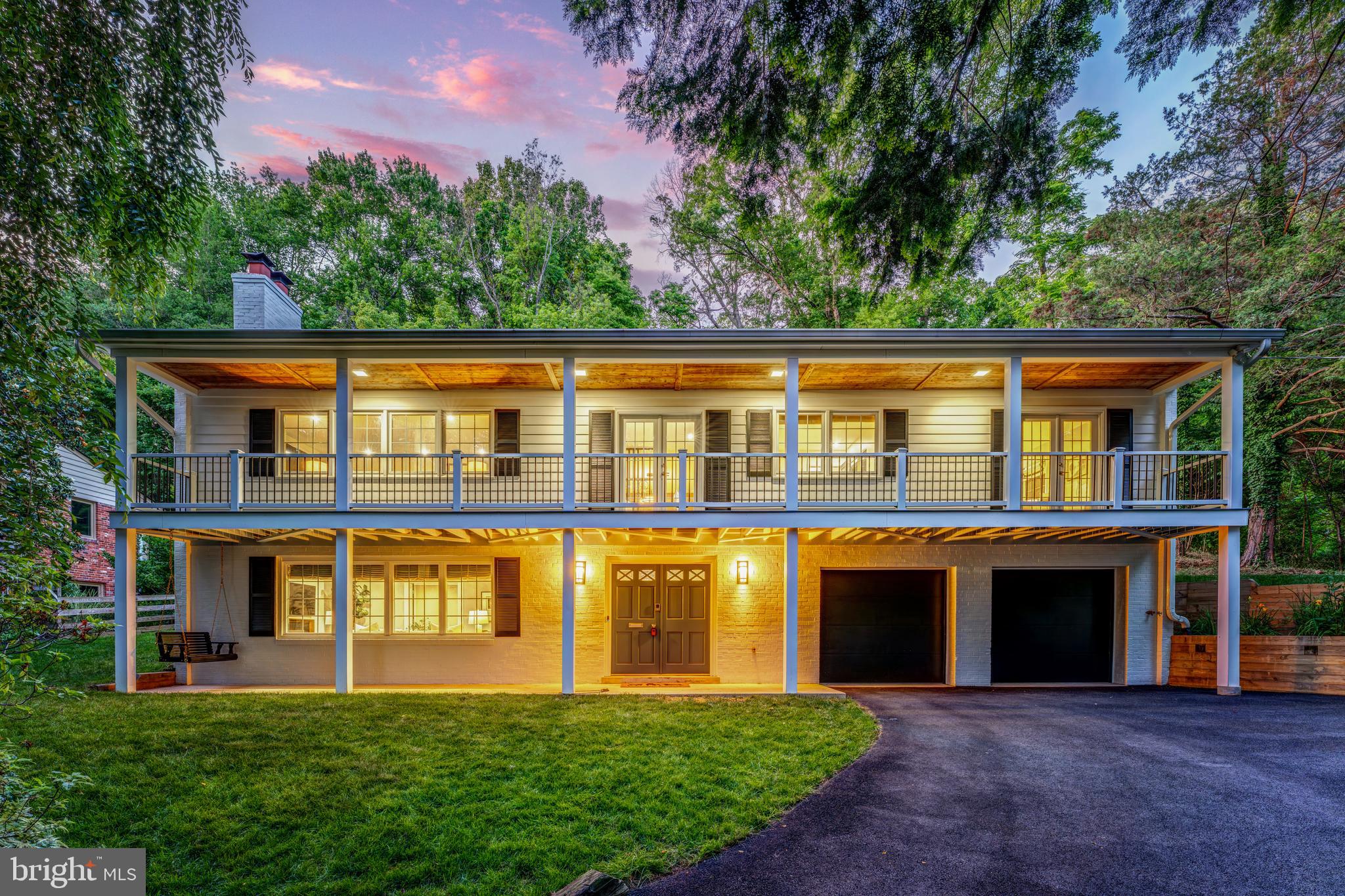 Set on more than a half acre in Lake Barcroft, 6310 Beachway Drive offers a rare combination of privacy, scale, and understated refinement in one of Falls Church’s most distinctive lake communities. A white painted-brick exterior, upper balcony, covered front porch, modern black garage doors, and mature landscaping give the home a gracious Southern-influenced Colonial presence, while the interior has been thoughtfully updated with hardwood stairs, iron railings, five-panel doors, hard-surface flooring, designer lighting, and generous natural light throughout. The entry level functions as a complete in-law suite with its own full kitchen, large bedroom, full bath, laundry, rec room with fireplace, and storage, creating exceptional flexibility for extended living, guests, or long-term stays. Upstairs, the main living level is open, bright, and polished, with three well-sized bedrooms including the primary suite, a refreshed primary bath, an upgraded secondary bath with dual sinks, designer tile, and a frosted glass shower enclosure, plus a large family room with fireplace and an adjoining flex area ideal for an office or sitting room. The kitchen is a standout, designed with 42-inch rich blue soft-close cabinetry, high-end quartz counters and backsplash, a deep stainless apron-front sink, a large picture window overlooking the trees, bar seating at the peninsula, a built-in Sub-Zero refrigerator, Wolf range, custom hood, drawer microwave, and a beautifully finished wine display closet. The formal dining room sits just off the kitchen and opens naturally to the main living space, while two access points lead to the upper balcony with filtered lake views. The rear of the home backs to trees, giving the property a quiet, private feel, and the finished two-car garage includes epoxy flooring, finished walls, a Tesla charger, and additional utility. Notable updates include newer windows, a tankless water heater installed in 2018, roof and HVAC both replaced.  Life in Lake Barcroft is centered around a private 135-acre freshwater lake with five resident-only beaches, boating, kayaking, paddle boarding, fishing, swimming, picnic areas, community events, clubs, and a beloved July Fourth weekend fireworks tradition, all just minutes from Seven Corners, Falls Church City, Arlington, Tysons, major commuter routes, East Falls Church Metro access, and Washington, D.C.