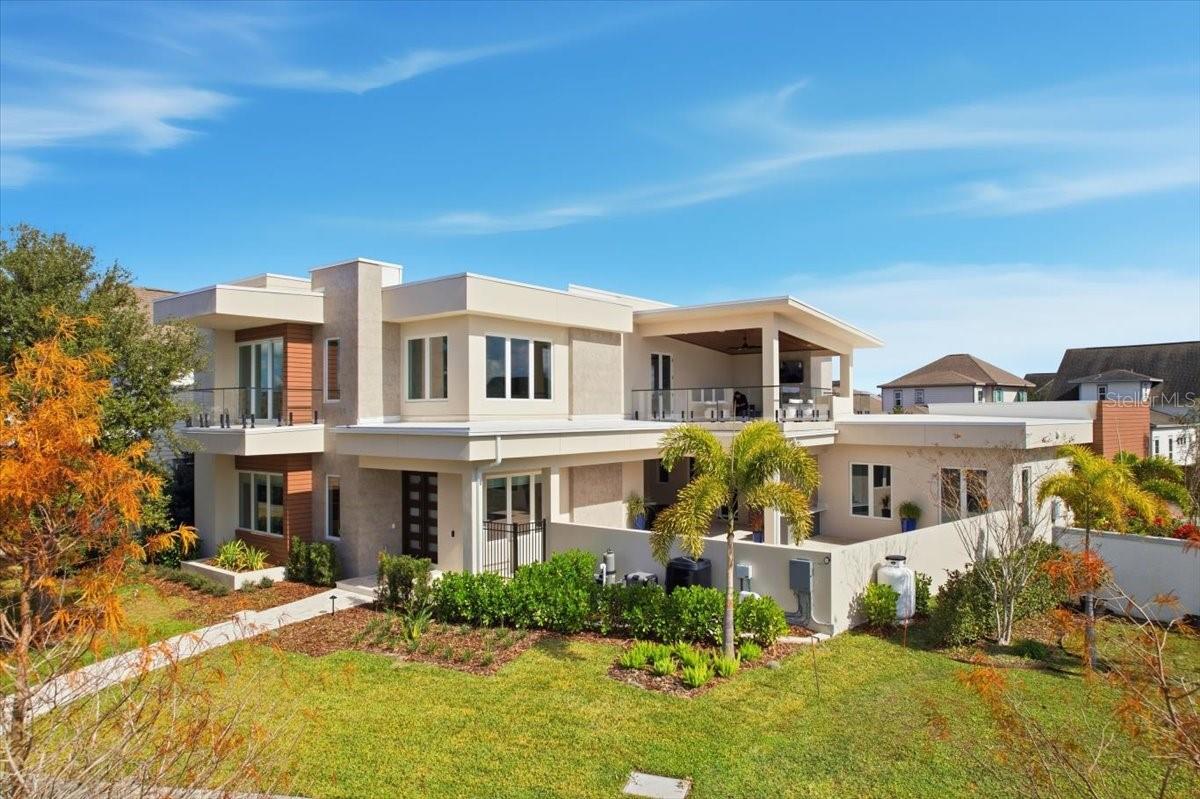 This exceptional DeVoe Custom Home is a showcase of architectural mastery, contemporary craftsmanship, and elevated modern living, perfectly positioned in the heart of Lake Nona’s Laureate Park, a community celebrated for its wellness-focused lifestyle and innovative design. Offering 4,460 square feet of thoughtfully curated living space, the residence offers 4 bedrooms and 4 bathrooms, with the flexibility to transform one bedroom into a private office. Every room and window offers stunning views from every angle, ensuring natural light and captivating scenery throughout the home.The arrival experience is unforgettable, highlighted by a striking floating glass staircase that serves as a sculptural focal point, immediately setting the tone for the home’s elevated, modern aesthetic. Throughout the residence, premium quartz surfaces, bespoke finishes, curated designer lighting, and soft-close cabinetry reflect a meticulous commitment to quality and architectural integrity, while abundant storage solutions throughout ensure every space is as functional as it is refined.At the heart of the home, the chef’s kitchen is designed for both culinary excellence and effortless entertaining. Outfitted with Sub-Zero appliances, custom cabinetry imported from Spain, and soft-close drawers, the space flows seamlessly into the main living areas, making it equally suited for intimate dinners or lively gatherings.The first-floor primary suite is a true private sanctuary, thoughtfully designed with wellness and luxury in mind. The spa-inspired bathroom is a study in indulgence, featuring heated floors, a glass-enclosed soaking tub and shower for a resort-style experience, and a color-changing Bluetooth-enabled sauna. Floating cabinetry, illuminated LED mirrors, and a custom walk-in closet with built-in organization complete the suite, showcasing the home’s intentional attention to detail and craftsmanship.Upstairs, a theater room and expansive bonus living area with a mini kitchen equipped with commercial-grade appliances provide exceptional versatility. With direct access to a private balcony and a separate exterior entrance, this level can function beautifully as a guest suite, multigenerational living space, or secluded retreat, all with sweeping views from every vantage point.One of the home’s most captivating features is the expansive balcony overlooking the lake, a rare offering in Laureate Park, designed to frame sweeping water views and extend the living experience outdoors. The main-level outdoor spaces are equally impressive, featuring a luxury custom pool with lake views and a fully equipped summer kitchen, creating the ultimate setting for seamless indoor-outdoor entertaining.The two-car garage is designed for both function and luxury, complete with a car lift, custom racks, built-in cabinetry, and abundant storage, offering a highly organized and versatile space for automotive enthusiasts or hobbyists. The home also benefits from three distinct points of entry: a front entrance facing the lake, a rear entry near the garage, and a private side entrance — providing added privacy, convenience, and natural flow throughout the property.This DeVoe Custom Home represents a rare opportunity to own a residence of architectural distinction, where refined design, uncompromising craftsmanship, and modern luxury converge in the heart of Lake Nona’s Laureate Park, with breathtaking views from every room and every window.