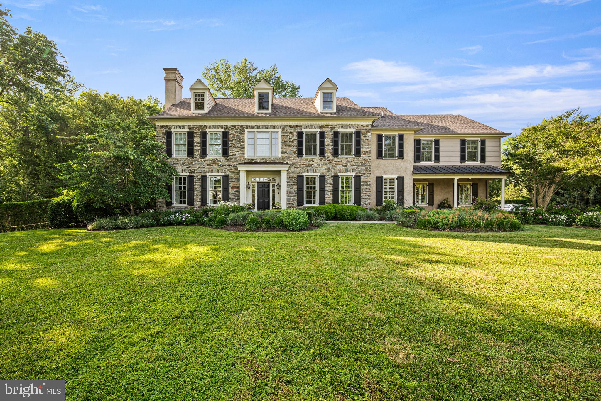 Exquisite Stone Colonial Manor Home in the prestigious Estate Section of Devon with over 7,500 square feet of exceptionally finished living space, situated on a beautiful prime acre of professionally landscaped grounds on a private corner lot with an oversized  pool and hot tub! This home was creatively designed and built by Ted Babiy and exudes impeccable craftsmanship in every detail including large arched cased openings to formal rooms, crown mouldings galore, walls of wainscoting, vaulted ceilings, lovely built-ins, and curved walls. Prepare to be amazed as you step inside this fabulous house designed for grand scale entertaining and busy day-to-day active living.  Approaching the front entrance with a stunning stone facade, a stone walkway is lined with beautiful and mature plantings. A handsome front door with sidelights and a transom window leads to the elegant front-to-back Center Hall that boasts an open 2-story turned staircase with a large landing to the Second Floor and a hall to the formal (1 of 2) Powder Room with a tasteful furniture vanity. The front of the Center Hall is flanked with two arched cased openings to the Living Room on the left and the Dining Room on the right. Gorgeous hardwood floors flow throughout these rooms as well as the Study/Gathering Room adjacent to the Living Room, and all have oversized crown mouldings. The formal Living Room is complete with a lovely gas fireplace with black marble surround and hearth and is encased with floor-to-ceiling wainscoting. The formal Study with French doors to the rear of the Center Hall is currently set up as a cozy Sitting/Gathering Room for intimate conversations and boasts walls of windows including a bump out/nook. The formal Dining has beautiful wainscoting and convenient access to a Butler’s Panty complete with marble wet bar and built-in cabinetry. The recently renovated state-of-the-art Kitchen is an absolute must see! Cleverly designed with “stations” for various activities/needs, it offers timeless cabinetry with refreshing- not your ordinary- quartz counters, a large island with seating and additional sink, one-of-a-kind oversized refrigerator/freezer with wine refrigeration in the middle, water purification for healthy modern living, two dishwashers, a 6-burner gas range, double wall ovens, one with a steamer, under counter built-in microwave, appliance cabinet with built-in counter, separate standing Scotsman icemaker, and a beverage refrigerator. There is also a built-in desk area with standing desk and printer stand! Everything was thought of to make the most functional Kitchen! The Kitchen is open to the Breakfast Room with a vaulted ceiling and French doors to the outside terrace/pool/hot tub oasis as well as the Great Room/Family Room. The Great Room offers a wall of built-ins for your entertainment needs, a gas fireplace with slate surround and raised slate/stone hearth with traditional wood mantle and glass doors, a magnificent Palladian window, and French doors to the Terrace for outdoor dining. There is a Rear Hall with multiple closets, an  informal Powder Room, and a Mud Room with beadboard walls and built-in bench seating. The Second Floor is home to a luxurious Primary Bedroom Suite complete with Sitting Room, fully outfitted walk-in closets, and sumptuous Primary Bath, 4-5 additional Bedrooms and Suites all with hardwood floors, one of which has built-ins and is currently used as an Office, 3 additional full Bathrooms, a large walk-in Linen/Storage Closet, and the Upstairs Laundry Room (1 of 2).  The Third Floor has a large finished Recreation Room with two built-in window seats as well as built-in shelving, a large Storage Room, and Attic space. The Lower Level is sprawling and includes a Game Room, 2nd Family Room with what could double as a 2nd Kitchen (dishwasher, sink, cabinetry), Exercise Room, the 5th Full Bath and 2nd Laundry Room, an enormous Storage Room, and finally an outside entranceto the Pool & Rear Grounds.