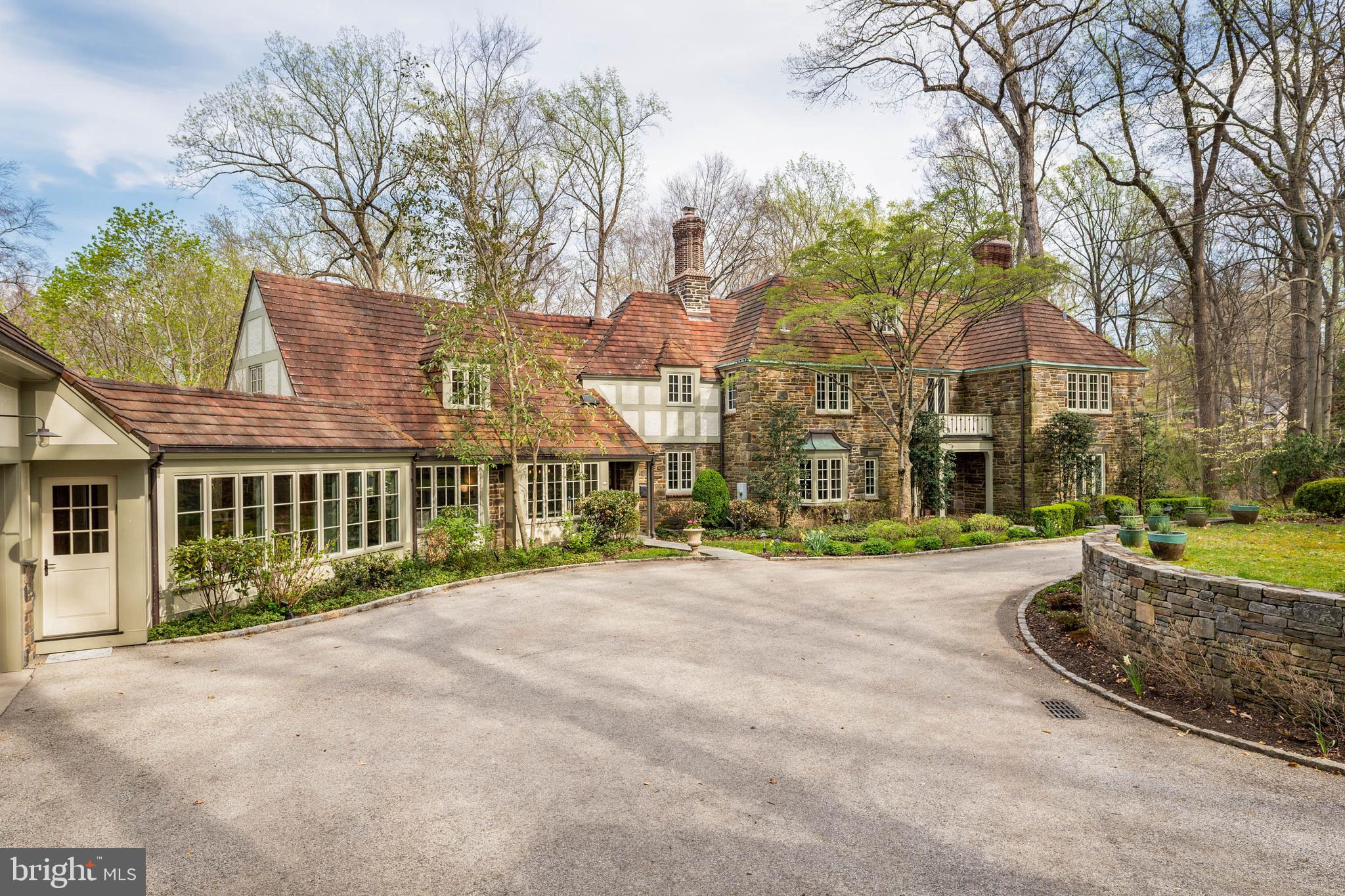 Open house Sunday April 19 Cancelled! Set on 1.76 acres, this stone Colonial is defined by its elevated setting, architectural proportions, and a level of craftsmanship rarely reproduced today. A courtyard approach introduces the home and reinforces its architectural presence. The exterior reflects the character of the Main Line’s most established homes, with stone construction, detailed trim work, and arched openings.The home is set within a mature, tree-lined landscape with views from nearly every room. It remains just minutes from Suburban Square, Ardmore, and the Main Line’s primary amenities.A center hall entry introduces the original portion of the home, where a paneled library, formal living room with fireplace, and dining room retain their architectural integrity with detailed millwork, beamed ceilings, and random-width hardwood floors. French doors connect the main living spaces to several flagstone terraces, extending the living areas to the outdoors.  A beautiful first floor bedroom with built ins and a fireplace  with easy access to full bath complete this level.The home transitions into a fully reimagined kitchen, dining, and family room, designed as the home’s central gathering space. A vaulted ceiling, expansive windows, and direct access to the grounds bring in natural light throughout the day. The kitchen is equipped with high-end appliances, a large island with seating, and adjacent informal dining, all flowing seamlessly into the family room.Supporting spaces include a butler’s pantry, mudroom with secondary entrance, and a sunlit gallery connecting to the three-car garage.A privately positioned upper-level suite above the garage, accessed by a separate staircase, offers flexible use as a home office or additional bedroom with full bath, well suited for guests, work, or separation from the main living areas.The primary suite is located within the main bedroom level, offering windows on three sides, two walk-in closets, and a renovated bath with heated floors. Each of the 3 additional bedrooms is en suite, providing comfort and flexibility for both everyday living and hosting.The outdoor setting includes terraces overlooking the pool and surrounding landscape, creating distinct areas for dining, entertaining, and quiet use.Improvements include a three-car garage with finished space above, updated kitchen and family room, guest suite on the main level, multiple HVAC replacements, rebuilt chimneys, refinished floors, and enhanced landscaping.This is a property that combines architectural character with modern livability in a setting that feels established, yet remains closely connected to everything.