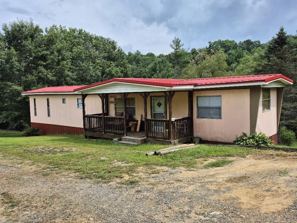 If you've been searching for a peaceful place in the country with room to spread out, this one is worth a look! This unrestricted property offers a beautiful pond, multiple springs, and plenty of possibilities for enjoying the land. Relax by the pond at the firepit and swing, or take in the tranquil water views from the back deck. A portion of the acreage could easily be fenced for horses or other livestock, making this a great option for a small homestead or mini-farm.  The rustic singlewide has received several recent updates, including a newer roof, underpinning and front porch, along with new lower kitchen cabinets, countertop and sink. The main bedroom features a custom shiplap wall headboard and a tongue and groove pine ceiling that adds to the home's cozy country character.  Water is supplied by a spring-fed tank system, and there is also a second springhouse on the property. Two storage buildings provide additional space for tools, equipment and outdoor gear. The established landscaping really comes alive in the spring with gorgeous perennial flowers throughout the property.  Tucked away in a peaceful, tranquil setting yet convenient to the Town of Fries, Independence and Galax. Outdoor enthusiasts will love being close to the New River and New River Trail for fishing, kayaking, biking and exploring.  Whether you're looking for full-time country living, a weekend getaway, a recreational retreat or a place to bring your horses and enjoy the land, this property offers the freedom of unrestricted acreage and a setting that invites you to slow down and stay awhile.