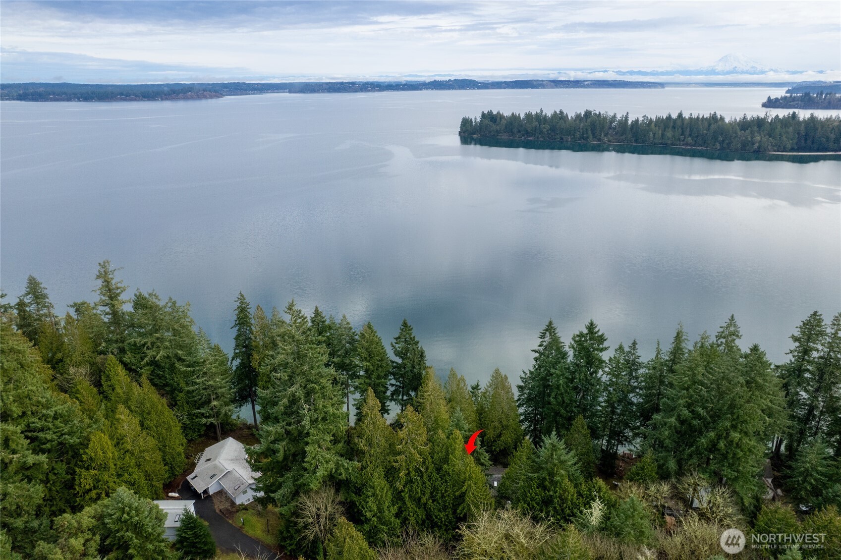 An incredible opportunity to own two truly special waterfront properties. Step back in time with vintage charm—the décor may echo the 80s and 90s, but the views and beach are timeless. First time on the market, this property features two homes perched above Mayo Cove, overlooking Carr Inlet, views of Mt. Rainier and approximately 180 feet of waterfront. Walk down the gently sloped path to skip rocks, swim or relax.  Boaters paradise & right around the corner from Penrose State Park.   Ideal for your own staycation, multi-generational living, or living in one home while renting the other. Very quiet, removed from the city noise but conveniently located just 12 minutes from Key Center and 30 minutes to North Gig Harbor.  The main home, an A-frame design, approx. 2110 sq. ft. offers two bedrooms. The main level features an open-concept living and kitchen area, a bedroom, and a full bath, with the second bedroom located upstairs. The fully finished basement includes two bonus rooms, a ¾ bath with laundry, and access to the one-car garage.  The detached, approx. 1101 sq. ft. ADU lives large & offers one bedroom, a full bath, and main-level living, plus a generously sized bonus room and an additional bath upstairs. Unfinished room perfect for shop or dry storage & 1 car attached garage.  With just over an acre, the possibilities are endless—ample room for raised garden beds, lush green grass, or keep as is and simply let nature take its course.    Welcome to the beach.