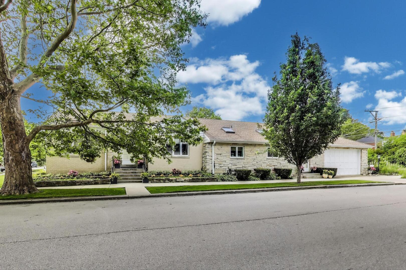 Elegant Brick & Stone Sauganash Step Ranch in Prime Location. Welcome to this beautifully maintained, corner step ranch nestled on a tranquil, tree-lined street in the heart of Sauganash-one of Chicago's most sought-after neighborhoods. With striking Lannon stone and brick exterior, this home boasts timeless curb appeal and a serene setting near two low-traffic, dead-end streets. Just steps from Sauganash Park, top-rated Sauganash Elementary and Queen of All Saints School, the Sauganash Trail, and the North Branch Forest Preserve, this location offers an unbeatable mix of urban convenience and natural beauty. Commuters will appreciate easy access to I-94, Forest Glen Metra, and neighborhood favorites like Whole Foods, Starbucks, Alarmist Brewery and more. Inside, you'll find a thoughtfully designed floor plan featuring walnut and oak hardwood floors, a formal living and dining room, and two dedicated home office areas-ideal for remote work/work from home. Retreat to the timeless spa-inspired fully upgraded bathroom, showcasing marble finishes and high-end Kohler fixtures complete with Rainhead shower, soaker alcove bathtub, Ralph Lauren triple sconce, AERIN Lighting and large built in grand recessed medicine cabinet mirror. The chef's kitchen is the heart of the home and includes: KitchenAid 36" built in wood paneled refrigerator, Heartland Metro gas stove, DSC/Fisher Paykel dual dishwasher, Dacor built in microwave, custom cherry and glass cabinetry, and large island. The kitchen has seamless flow into the cozy family room, complete with wood-burning fireplace. Waterford light fixtures in the main hallway and primary bedroom. The finished basement offers a second built in home office spacious recreation room/play space, half bath, and dedicated laundry area with GE HE washer and dryer and sink. The basement includes a POTENTIAL FOR FOURTH BEDROOM. Additional features include: two Zoned gas-forced air & central A/C systems; Attached 2.5-car garage; and outdoor patio- perfect for friends and family entertaining. Roof 2018, HVAC 2021,Sump pump 2025. A rare opportunity to own a move-in-ready home in Sauganash!