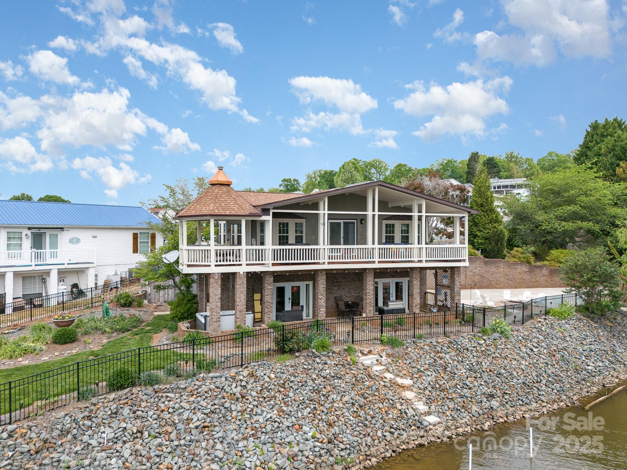 Welcome to your waterfront sanctuary overlooking the majestic Badin Lake, where every day brings breathtaking views and unforgettable sunsets. Entertain guests or simply unwind on the upper-level gazebo on the deck, retreat to the amazing covered porch for peaceful moments by the water's edge or unwind in the hot tub on the lower-level patio while taking in the captivating sunset. The beautifully landscaped and fenced yard creates the ultimate outdoor living space, perfect for enjoying the fresh air and natural beauty. Inside, discover three bedrooms and three full baths, including a primary suite with ensuite bath. The open concept kitchen, dining, and living space offers not just functionality but also breathtaking views of the serene waters of Badin Lake. The lower-level den provides additional comfort and versatility while the third bedroom doubles as an office space, Embrace the lake lifestyle in this extraordinary retreat where tranquility and luxury unite.