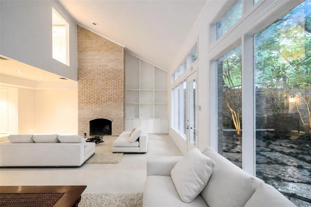 Chic mid-century modern townhome in gated Christopher Place, one block from Katy Trail on Turtle Creek with private creekside park. Rarely available, this 1960s residence underwent a meticulous four-year professional restoration highlighting its original architecture and brickwork, complemented by hand-poured white terrazzo floors, bespoke doors and fixtures, art-focused walls and lighting. A dramatic 21-foot skylight crowns open-air dining room, while expansive windows and 17-foot ceilings fill twin living areas with natural light and private patioed garden views. Original two-story solid-brick fireplace with gas option anchors sunken seating area that includes built-in media cabinets and new fiber cable. Lots of storage! Large open kitchen features custom Downsview cabinetry, quartz surfaces, Bosch dual ovens and gas cooktop with new stainless steel KitchenAid double-door fridge. Powder bath includes top-of-the-line, in-wall, Geberit fixture and bespoke sconces with heavy white Carrera marble slab counter and backsplash. Two upstairs suites with ensuite baths include French Brown teak floors, custom cabinetry and TOTO fixtures. Large primary suite offers four sizable custom closets and serene European marble bath with new skylights, a cedar-paneled hot rock sauna room, cast-iron garden tub, separate glass-enclosed shower and 90” floating double vanity. Bath overlooks lighted garden with mature oak and crape myrtle trees, and night-blooming jasmine. Meticulously kept as a pied-à-terre---offering a rare opportunity for authentic mid-century architecture with Dallas' best amenities at your doorstep. Thoughtfully curated, with elevated finishes, versatile spaces, and indoor-outdoor living. Walk, run, bike and entertain in Uptown’s coveted Turtle Creek corridor.