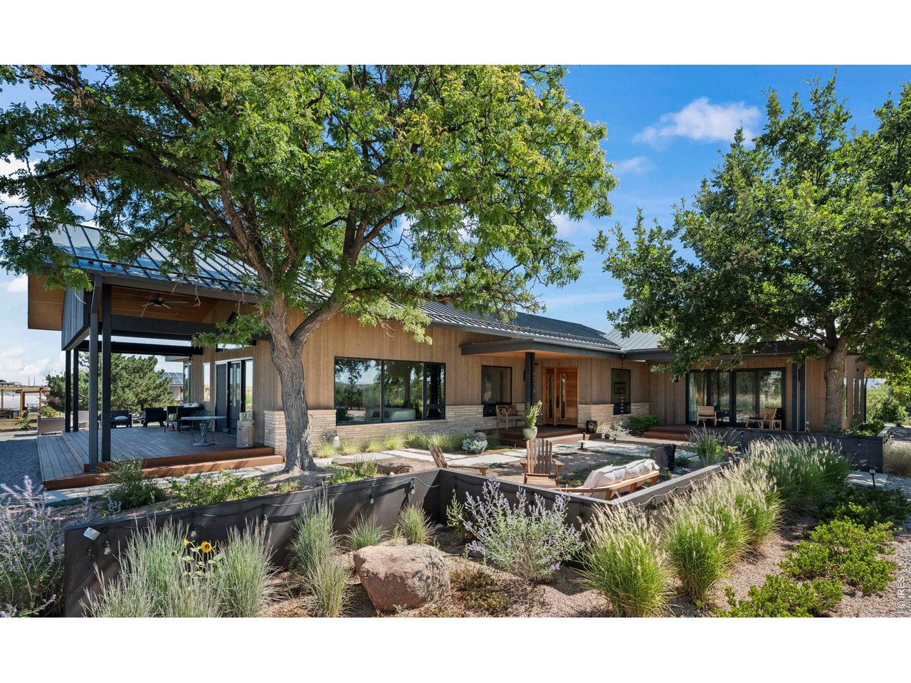Distinctive without feeling formal, and luxurious without excess, this is a one of a kind offering for those seeking design, land, and lifestyle in equal measure. Panoramic, unobstructed mountain views await from this modern ranch home on 10 acres. Designed by BLDG.Collective and completed in 2023, it boasts light filled rooms with thoughtful finishes throughout. The chef's kitchen is anchored by 10' soapstone island and an AGA Mercury 48" Induction Range. A sliding pocket window connects the kitchen to the sweet 4 season Sun Room. The family room, with sliding barn door separating it from the main living area, features a private bedroom suite with 3/4 bath, loft, wet bar with brass sink. and beverage frig. The primary retreat offers a spa-inspired 5-piece bath with soaking tub, multi-fixture shower, and private deck overlooking Colorado's plains. The lower level features a large rec room, kitchenette with granite counters and full-size refrigerator, the 3rd bedroom and full bath, plus a sun-filled walkout solarium. Medicinal and native plant gardens lead to the barn with 2 horse stalls, tack and work areas, plus a hay mow. A flex space with large kitchen, bath, office and shaded porch is a super added bonus. Cedar cladding and natural stone complement professionally xeriscaped grounds with drip irrigation, pollinator-friendly plantings, gravel pathways, custom steel walls, and a bubbling boulder water feature. Organic soil building over 10 years created a low-water landscape and thriving business opportunity. The pasture land extends north to protected Boulder County open space, with White Rock trailhead less than a 10-minute walk away. Other features include a 14'x24' greenhouse, Gazebo, 30kW owned solar system, geothermal, oversized 6-bedroom-rated septic system, 2 EV outlets, large paddocks, round pen and and arena. This thoughtfully designed and curated home/farm is truly one of a kind!