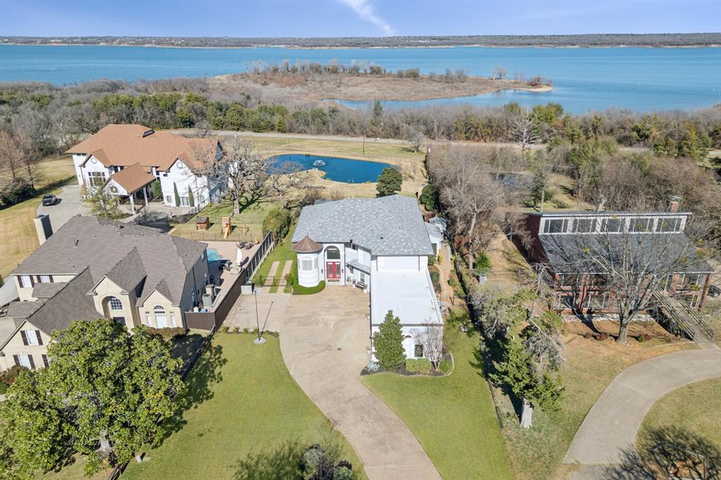 Extraordinary opportunity to own a stunning property with sweeping Grapevine Lake views amid gorgeous mature trees and custom homes. This idyllic location offers a tastefully updated residence designed to both live in comfort and entertain with style. Designed with lake views in mind, the property provides ample opportunity to enjoy the beauty of water, wildlife, and wonderful landscaping. At just under a half-acre and 4,000 SF, this home is anything but cookie cutter, featuring a rare 4-car garage, 4 bedrooms, 3.5 bathrooms, glass-enclosed sunroom, 2 office spaces, upstairs loft, boat parking, and multiple side and rear patios and gardens. The intentional layout maximizes spectacular views from both levels, including the main-level office, primary bedroom and bathroom, great room, and an upstairs catwalk and balcony. Flooded with natural light, the interior balances open gathering areas with private spaces. Extensive remodeling in 2023 includes added square footage of a main level bedroom and bathroom, over 50 new energy-efficient windows, interior and exterior paint, updated AC and hot water systems, new fireplace, new hardwood flooring on main level and stairs, new carpet in bedrooms, new kitchen appliance, 5-burner gas range, new plumbing fixtures, professionally painted cabinets, new cabinet hardware, updated ceiling fans and light fixtures. Outdoor living includes a deep pool with PebbleTec finish, new tile, and new digital pool equipment, expanded paver decking, new paver patio off the kitchen, pergola, and upgraded landscaping and irrigation. The huge garage was improved with epoxy flooring and has ample space for 4 vehicles plus a bump out for storage and tools. Located in a quiet neighborhood within ten minutes Southlake Town Square, Grapevine Historic Downtown, and recreational and dining options, this home combines expansive views, thoughtful updates, and a highly desirable setting.