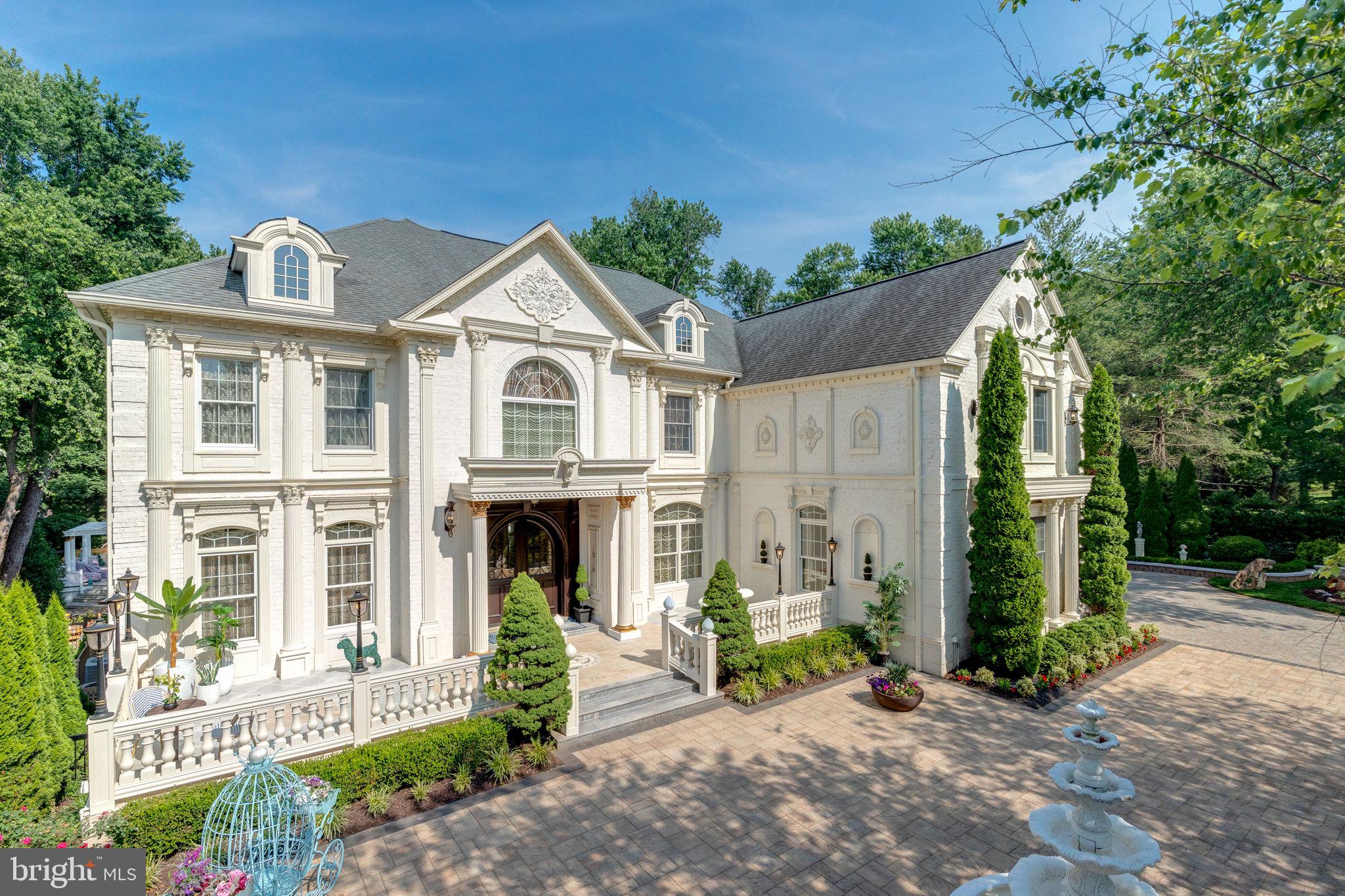 Exquisite artistry, quality craftsmanship, and a touch of glamour combine in this spectacularly appointed 11,000+ sq. ft. manor, set on .89 lush acres. Sited near the Potomac River and moments from the quaint shops and fine dining of Great Falls village, this impressive estate showcases luxurious living at every turn.A grand marble foyer sets the tone, with lighted recesses, gold-gilded trim, and sweeping views of the home’s richly designed interiors. The formal living and dining rooms feature antique mirrors, crystal chandeliers, intricate ceiling medallions, and decorative hardwood floors with inlaid wool carpeting.At the heart of the main level, a breathtaking reception area rises two stories, offering an ambiance of elegance and exceptional detail. The richly paneled library is clad in hardwood and features a fossil-stone granite wall with built-ins and fireplace. A coffered-ceiling drawing room includes 11 glass showcases—perfect for art or collectibles. Nearby, a bright music room with bamboo flooring and iron chandelier offers quiet refuge.The chef-caliber gourmet kitchen impresses with an 8x5 ft. “Louise Blue” granite island and premium appliances. A granite breakfast bar and informal dining area complete the kitchen. Adjacent, a vaulted solarium with bamboo ceiling and French doors opens to expansive decks and lawns, ideal for indoor-outdoor entertaining.Additional amenities on this level include a paneled elevator, pantry, butler’s pantry with copper sink, mud room, and direct access to the 4-car garage.Upstairs, the opulent owner’s suite is a private sanctuary that features a tray ceiling, Brazilian cherry flooring with a 100% wool inlay rug, and a cozy sitting area with silk carpet before a marble fireplace and media screen. A morning kitchen offers private refreshment.The walk-in gallery closet is a boutique experience, with Thomasville cabinetry, center Travertine island, cedar-lined wardrobes, and chandelier-lit tray ceiling. The spa-like primary bath stuns with a central soaking tub before an electric fireplace, dual vanities with 24k gold-gilded sinks, media-screen mirror, and a separate commode room with decorative vanity. Glass-enclosed steam and marble showers, stone seating, and mosaic tilework complete the indulgent space.Three additional bedroom suites each feature designer bathrooms and walk-in closets. A full laundry room with LG washer/dryer and whirlpool sink completes the upper level.The lower level embraces a sleek, club-like vibe. Descend via curved staircase with leopard-print carpet to a modern lounge featuring a golf simulator, lighted mosaic bar, billiards area, and expansive rec room—ideal for lively entertaining.A dramatic home theater, entered through a historic Hotel Washington door flanked by theater masks, includes a custom wool carpet medallion, three-tier leather seating, granite bar, and immersive surround sound.Also on this level: a 5th bedroom with spa bath, sauna and steam shower; a Tuscan-style wine cellar and tasting room with stone and granite walls; and a utility closet with stacked washer/dryer for guests or staff.Outdoor living is equally impressive. Walk out to a tiered granite terrace with a summer kitchen, built-in BBQ, and stone fireplace. A generous deck overlooks landscaped lawns and a newly built pool, plus a hot tub with recessed TV and radio—perfect for private relaxation or elegant entertaining.