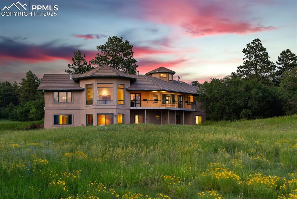 This one-of-a-kind custom walk-out rancher is positioned to maximize some of the most stunning views of Pikes Peak perfecting positioned on a private 5.12 acre lot in Bridle Bit Ranch * Nestled in the Pines and designed with exceptional craftsmanship, this one owner home is loaded with style * Offering a seamless blend of comfort and functionality, this home is ready for your creative eye as some updating is needed * The main level showcases travertine, hardwood and tile flooring throughout, anchored by a dramatic radius great room with a wall of windows that flood the space with natural light and the most AMAZING Pikes Peak views * A dual-sided fireplace connects the great room to the formal dining area, complete with a full wet bar, perfect for gatherings and entertaining * The gourmet kitchen is outfitted with granite countertops, a 6-burner Dacor range, double ovens, raised dishwasher, appliance garages and a spacious walk-in pantry * Richly appointed library offers a steel, spiral staircase leading to the “Eagle’s Nest,” a truly unique space with incredible panoramic views, ideal for quiet reflection or creative inspiration * The luxurious primary suite features a spa-like bath, seamless corner window with massive views, walk-in closet and direct access to a large laundry/craft room * The walk-out lower level includes a spacious family room, second wet bar with solid stone counters, dishwasher and beverage fridge, plus two additional bedrooms with a Jack-and-Jill bath, an exercise room, and potential for a fifth bedroom * The enormous workshop includes garage door access to an additional oversized 2-car garage—perfect for car enthusiast | hobbyists or storage * Radiant in-floor heating throughout, Pella triple-pane windows and high ceilings to create plenty of custom appeal and drama * Oversized 4 Car Garage, WOW * Exciting tile floored decking enhances your outdoor living experience * This is a truly special home that must be experienced in person * Look Now!