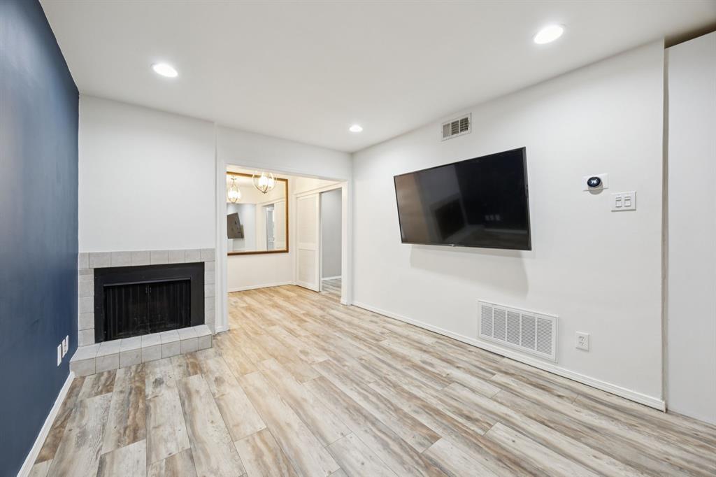 Unfurnished living room with wood finished floors, a tile fireplace, recessed lighting, and a chandelier