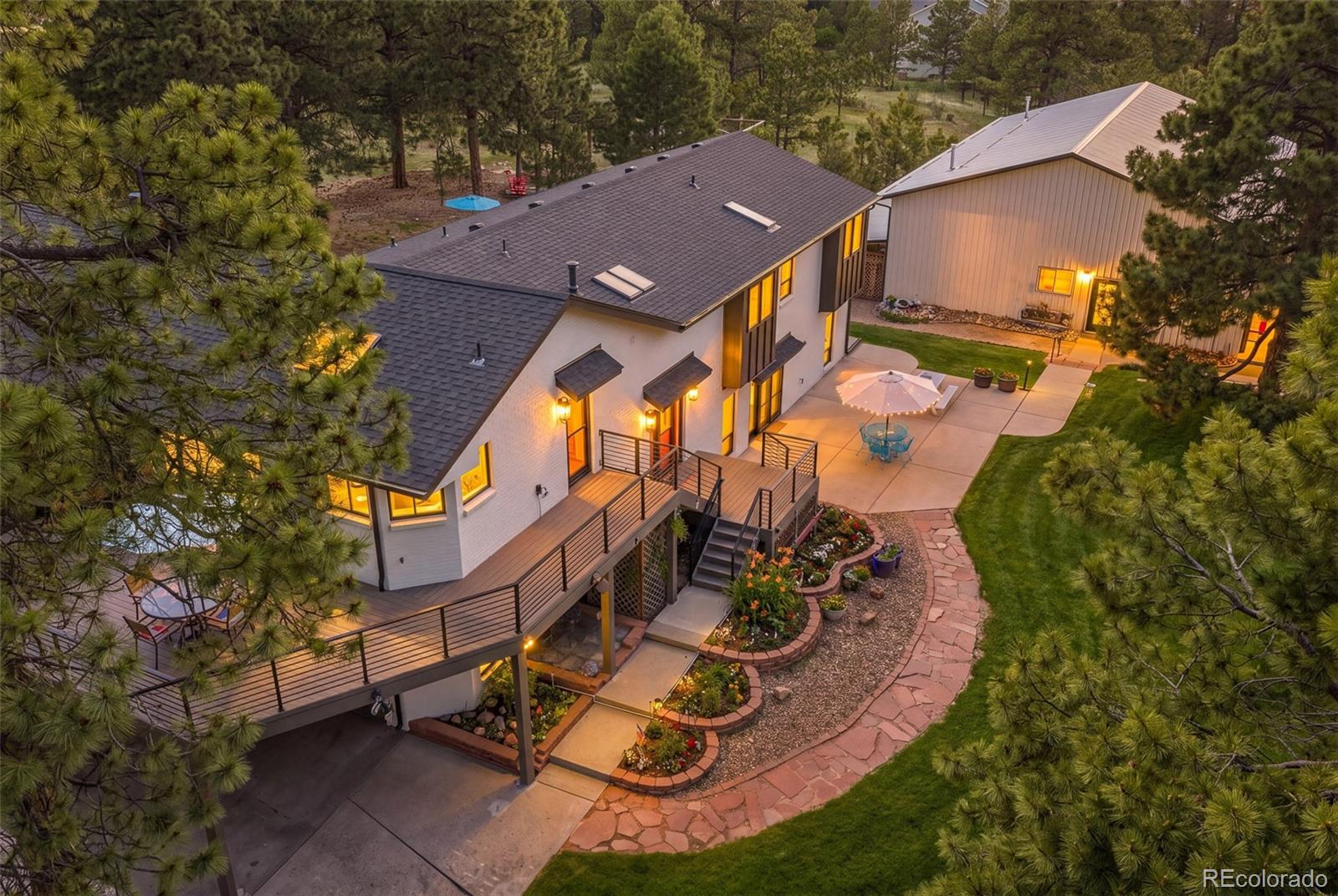 Welcome to The Tree House, a character-filled Colorado retreat where wooded acreage, mountain views, outdoor living, and serious shop capability come together just minutes from town. Set on nearly five acres at the end of a cul-de-sac in The Hills at Bayou Gulch, this horse-friendly property offers privacy, usability, and convenience, with paved access, mature trees, neighborhood bridle trails/easements, and a setting that feels worlds away while remaining close to The Pinery Country Club, Colorado Horse Park, and Parker amenities.Experience multiple outdoor living areas, a finished walk-out lower level, wine/tasting room, RV parking and hookups, chicken coop, and a 64' x 42' heated and insulated shop designed for vehicles, trailers, equipment, or hobbies. Inside, the remodeled home is warm, inviting, and full of personality. Vaulted ceilings, exposed beam details, and large picture windows, create a main living area that feels open and connected to the surrounding landscape. The kitchen flows easily into the dining area and expansive outdoor deck, with a large island, walk-in pantry, generous prep space, and a layout designed for gathering.Unwind in the spacious primary suite with vaulted ceilings, tree-framed windows, walk-in closet, and five-piece ensuite bath. The finished walk-out lower level expands the lifestyle with a large recreation area, wet bar, two additional bedrooms, full bath, and a custom wine/tasting room with decorative metal entry, barrel-style tasting area, wine displays, and hidden storage.Outdoor living is central to the experience, with a wraparound deck, lower patio, hot tub, fire pit, mature landscaping, and a sunset viewing platform with mountain and meadow views. Whether it is morning coffee among the trees, horses, chickens, cars, tools, trailers, or simply room to breathe, The Tree House offers Colorado acreage living with character, capability, and convenience. See More At: https://www.9905bayouridgetrail.com/