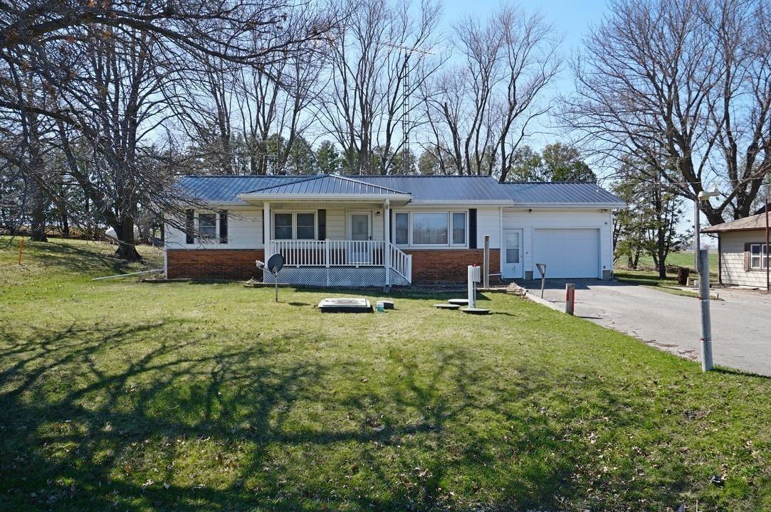 This country home is ready for your personal finishes! Situated on 0.41 acres just outside of town, the property offers a 3-bedroom home with a 1-car garage plus an attached storage/work space (23 ft x 16 ft) and 14 ft x 16 ft shed. A covered front porch welcomes you to the home and provides country views. The ranch-style home has a traditional floor plan featuring a living room that opens to the dining room and kitchen. Down the hall are a ¾ bath and 3 bedrooms.  Laundry hookups are available in one of the bedrooms and in the basement. The full basement has ample space for hobbies and storage, including a rough-in bath and workroom. Offered in AS IS condition. This property is full of equity opportunities!