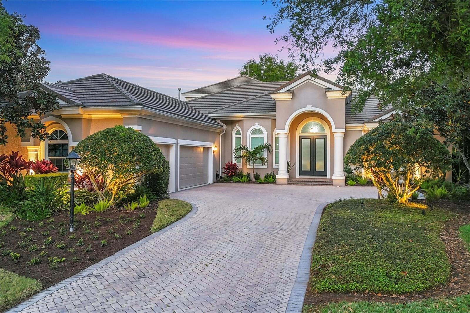 In sought-after Greystone enclave of Lakewood Ranch Country Club, this exceptional four-bedroom, four-bath plus den and bonus, which could serve as a fifth bedroom residence surpasses the finest new construction offerings, including impact windows and doors. Just a half mile from Lakewood Ranch Main Street, the home is enveloped by mature, lush foliage with a beautiful view of the golf course. Impeccably renovated in 2020, this residence redefines the standard of luxury living. Upon entering through grand glass double doors, you are greeted by an open-concept design, showcasing a cool, neutral color palette that exudes timeless sophistication. Soaring ceilings with exquisite detailing set the stage for an elegant living experience, while a stunning marble chevron-tiled fireplace creates a warm ambiance. Accordion-style impact sliders seamlessly connect the main living spaces to the outdoors, inviting alfresco enjoyment. The heart of the home is the gourmet kitchen, thoughtfully curated with new GE Café Series Matte White appliances, a generous counter-height island with ample storage, Taj Mahal Matte Leathered quartzite countertops and custom two-tone cabinetry with a range hood to match the island. A marble chevron tile backsplash, LED under-cabinet lighting, a spacious walk-in pantry with custom wood shelving and 15-inch upper cabinets with glass fronts for your cherished collectibles complete this culinary masterpiece. Go outside to a panoramic screen-enclosed lanai, offering breathtaking views of the lake and golf course, framed by tropical landscaping and mature trees. The heated saltwater pool, with its spa and serene water fountain, ensures year-round relaxation, while the newly appointed outdoor kitchen, featuring a KitchenAid grill, sink, refrigerator and quartz countertops, invites unforgettable dining under the stars. Shellstone pavers and new pool coping add to the outdoor oasis refined charm. The first-floor guest bedrooms are havens of comfort, each with new carpeting and fans, while the primary suite is a luxurious retreat, boasting hardwood floors, a tray ceiling, custom walk-in closets and a spa-like en-suite bath with a freestanding tub, dual sinks with quartz counters, a custom-designed walk-in shower with dual heads and elegant wood cabinetry with a glass display tower. The second-level suite is a sanctuary for extended family or guests, complete with a bedroom and spacious den that could easily serve as a fifth bedroom, a large walk-in closet, a spa-inspired bath with barn-style shower doors and a stylish morning kitchen, all with a private balcony offering an elevated retreat. Further enhancing this exquisite home are additional features, including newly painted interiors, crown molding throughout, all-new LED recessed lighting, newly refreshed landscaping and outdoor lighting, electric shades, new decorative fixtures, two 2020 air conditioner units, impact windows and doors, and an oversized three-car garage with golf cart storage. Lakewood Ranch Country Club offers world-class amenities, including a state-of-the-art fitness center, a clubhouse, a Junior Olympic-sized pool and access to three 18-hole championship golf courses. Ranked as one of the nation’s top-selling planned communities, Lakewood Ranch provides a lifestyle of unparalleled luxury with top-tier shopping, dining, schools and nearby pristine beaches.