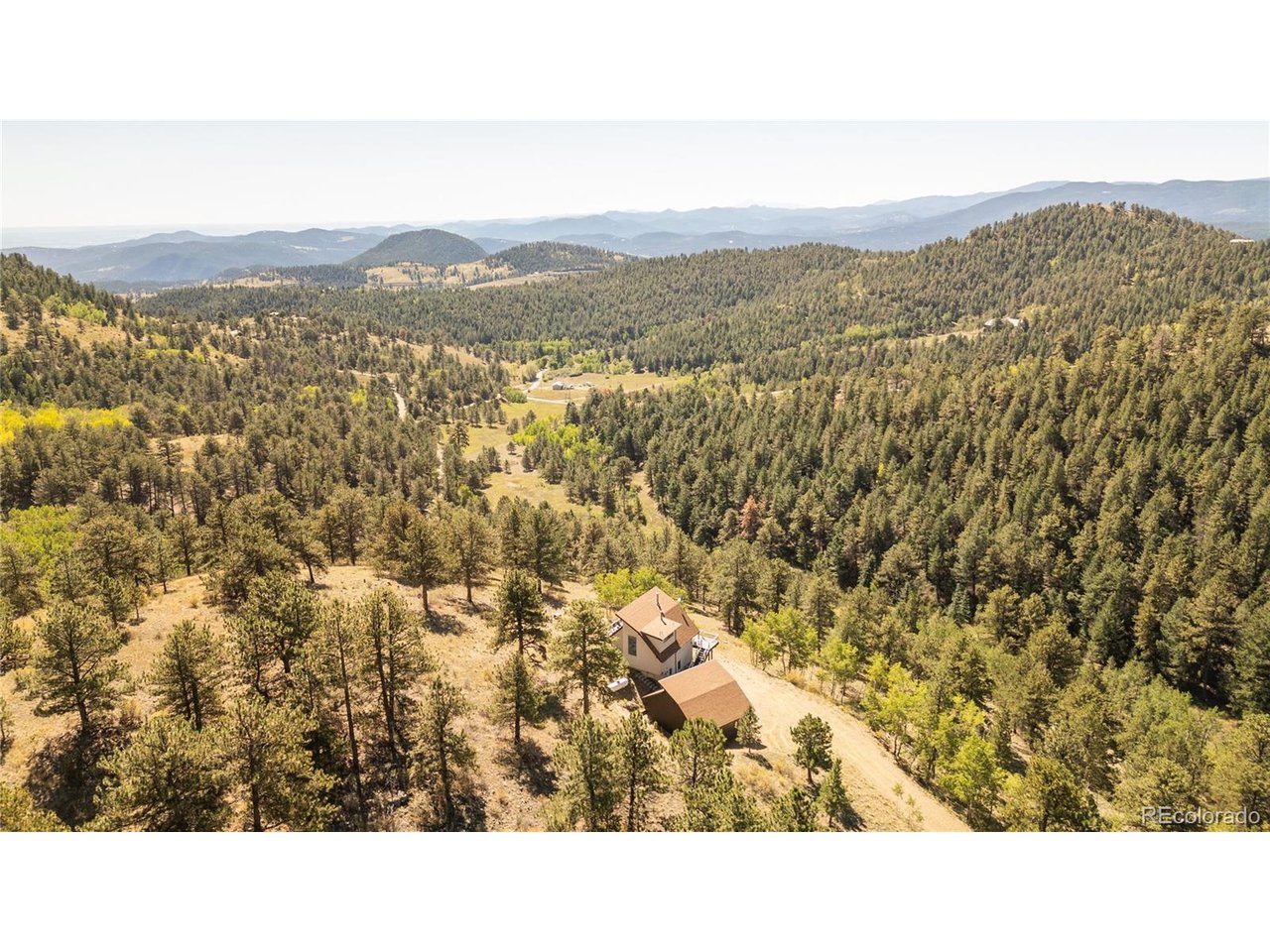 Tucked on 39 sprawling acres in Golden Gate Canyon, this newly renovated turnkey home offers a refined retreat surrounded by beautiful aspen groves and mountain views to Pikes Peak. Expansive windows frame the landscape, while vaulted wood ceiling details and an open living and dining area create an inviting sense of volume. The living area centers around the stunning views, complemented by a kitchen with generous cabinetry and a bar with a built-in beverage refrigerator. A spiral staircase leads up to a bedroom and a loft to an outdoor balcony, extending the home's connection to its surroundings. The first floor provides two generously sized bedrooms and a full size bathroom. Outside, a new Trex deck and stairs create a beautiful setting for taking in the mountain scenery. A three-car oversized detached garage and barn provide exceptional utility. Set on 39 acres, this property offers a spacious pasture complemented by a well-equipped barn featuring two horse stalls, hay storage, and a loafing shed provides a convenient setup for horse training and equestrian activities. Smart home features include Control4, remote shade and surround-sound controls for inside and outside speakers, Starlink and a full security system with five cameras. Thoughtful updates extend beyond the interior, including new stucco and exterior stonework, a whole-house water softener system, wireless main water valve controls, and plumbing for a washer and dryer. The property is also equipped with two low mileage ATVs, an owner-owned propane tank, private well, and recently inspected septic system for added convenience and independence. Just 30 minutes from Downtown Golden, 25 minuets from Coors Brewery and less than an hour from Downtown Denver, this mountain retreat offers the perfect escape from the city without sacrificing convenience. Leave the hustle behind and settle into the peace, privacy, and natural beauty of the mountains.