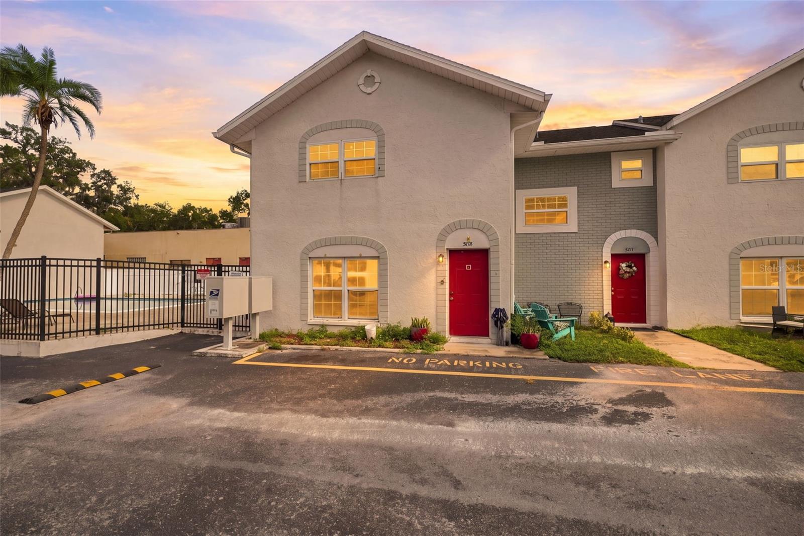 This inviting two-story, 2-bedroom, 1.5-bath condo offers bright living spaces, a comfortable layout, and convenient access to a community swimming pool just steps from the building. A light-colored stucco exterior with distinctive arched accents around the windows and entry creates a charming first impression, while a bright red front door welcomes you inside. Step into the spacious living room, where tile flooring and large front-facing windows fill the space with natural light, creating an inviting setting for relaxing or gathering with guests. A staircase with decorative metal railing leads to the second floor, while the main level flows easily into the dedicated dining area, where another large window keeps the space bright and the kitchen is just steps away. The galley-style kitchen provides wood cabinetry with abundant upper and lower storage, generous countertop space, a tile backsplash, stainless steel sink, tile flooring, and cabinets and drawers along both sides for an efficient workspace. Upstairs, Bedroom 1 offers a spacious retreat with multiple closets providing ample storage and plenty of room for a large bed and additional furnishings. Bedroom 2 provides generous open floor space and a flexible layout with room for a bed, dresser, desk, or other furniture. The full bathroom includes a single-sink vanity with cabinet storage, tile flooring, and open shelving, while the convenient half bath provides an additional single-sink vanity and mirror for guests. When it is time to unwind, head outside to the community swimming pool located beside the condo, where a spacious brick-paver deck, lounge seating, fencing, and gated access create an inviting place to enjoy sunny days close to home. Beyond the community, Downtown New Port Richey offers local shopping, dining, and entertainment, while Sims Park provides riverfront green space, walking paths, a playground, splash pad, amphitheater, and kayak access. Nearby James E. Grey Preserve offers another outdoor escape with natural surroundings, a riverfront boardwalk, picnic areas, kayak access, and opportunities to enjoy local wildlife.