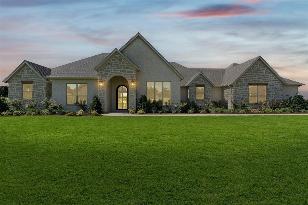 Showcase of Homes 2nd place winner! Welcome to this stunning new construction by Couto Homes, nestled on 1.048 acres in the sought-after Estancia Estates community in Parker County. This 3,214 sq ft Catalina Signature plan features 4 bedrooms, 3 bathrooms, study, game room, 3-car garage-all thoughtfully designed with a warm organic modern aesthetic throughout. Step inside through an oversized iron front door into a flowing open layout where full arch walkthrough openings, 8-foot interior doors & a coffered ceiling in the living room add architectural depth & character. At the heart of the home, the kitchen impresses with custom cabinetry in a rich stain finish, quartz apron-front sink, quartz countertops, large island, pull-out spice & utensil drawers, reeded glass upper cabinet doors & appliance suite including a gas cooktop, double oven, dishwasher & drawer microwave. Bronzed gold fixtures & under-cabinet LED lighting complete the elevated look. The living room centers around a gas fireplace with a floor-to-ceiling stone surround & a floating mantel. Engineered wood flooring flows throughout the main living areas, kitchen, hallways, entry, & game room, while the fireplace, 4-panel 12'x8' sliding doors & an oversized back porch with stained tongue-&-groove ceiling seamlessly connect indoor & outdoor living. The primary suite is a private retreat featuring a spa-inspired bath with freestanding soaking tub, walk-in frameless glass shower, bronzed gold fixtures & a direct connection to the utility room for added everyday convenience. The outdoor living space is built for entertaining with a fully equipped outdoor kitchen featuring a gas grill with LP regulator, stainless double access doors, island vent & stainless sink -all wrapped in a matching brick surround. Additional highlights include open cell foam insulation, radiant barrier roof decking, WiFi thermostat, landscaping package, front flower beds, perimeter gutters & epoxy-coated garage flooring.