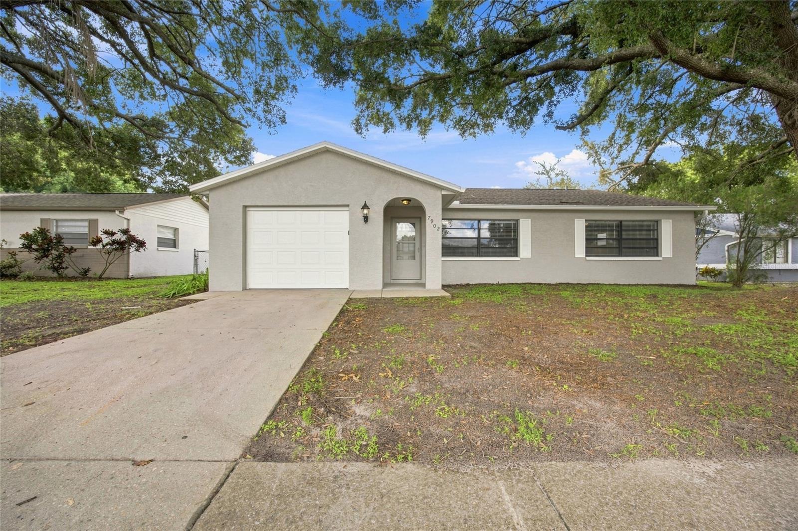 Pond-front living, a spacious screened lanai, and a permitted 2021 shingle roof highlight this inviting 3-bedroom, 2-bath home with 1,595 square feet and no HOA. The open interior features ceramic tile throughout the main living areas, vaulted ceilings, abundant natural light, and separate living, dining, and breakfast spaces. The kitchen offers generous cabinetry, ample counter space, a breakfast bar, pantry storage, and an over-the-range microwave. The primary bedroom includes a private bathroom, while two additional bedrooms provide flexible space for a variety of needs. Sliding glass doors open to an expansive screened lanai overlooking the fenced backyard and peaceful pond, creating an enjoyable setting for relaxing or entertaining. Additional features include central air, ceiling fans, window treatments, hurricane shutters, an attached one-car garage with door opener, public water and sewer, mature oak trees, and a convenient New Port Richey location near shopping, dining, recreation, and major roadways.