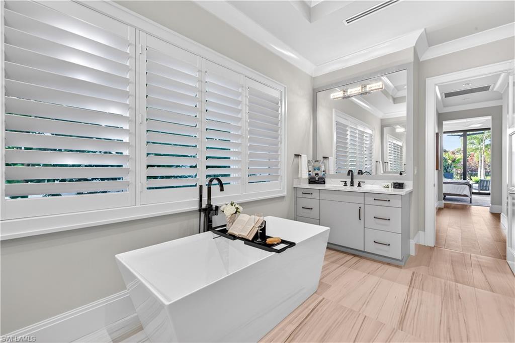 Bathroom featuring vanity, a soaking tub, and crown molding