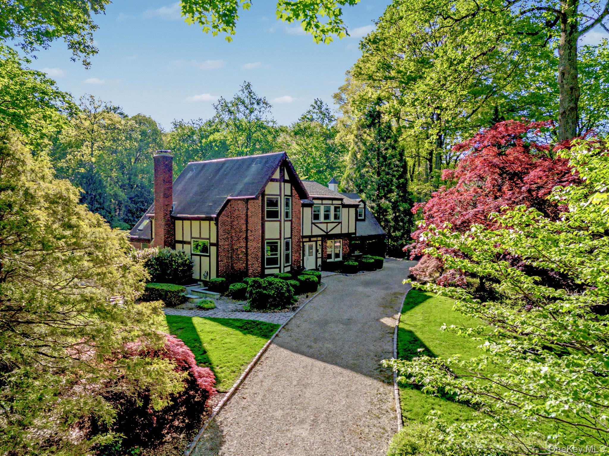 First time on the market from the original owner, this rare and uniquely captivating estate, 80 Hack Green Road, perfectly reflects its prestigious address. Privately set on almost three impeccably landscaped, completely flat acres between Scotts Corner and New Canaan, this distinguished brick and stucco colonial Tudor offers approximately 4,000 square feet of exceptional craftsmanship and timeless architectural character. Built by a professional contractor well beyond standard specifications, the home reflects enduring quality and meticulous updates throughout.A grand semicircular driveway welcomes guests with ample parking for up to twenty cars, creating a gracious arrival for grand-scale entertaining. Inside, thirteen custom stained-glass windows infuse the interiors with remarkable artistry and warmth. The heart of the home features a sunlit eat-in kitchen perfectly positioned between mudroom and the expansive great room with a 16-foot-high ceiling, which boasts dramatic skylights and a custom wet bar that opens seamlessly to the outdoor patio. A wood-paneled home office with built-in bookcases offers a quiet retreat overlooking the gardens, while a cozy recreation room features a high-efficiency cast-iron wood-burning fireplace. A whole-house central audio system effortlessly serves the main living spaces, making it highly functional for both vibrant social gatherings and quiet everyday living.The residence offers four bedrooms (originally 5) and three-and-a-half beautifully updated bathrooms. A vaulted upper-level bonus room, originally designed as a fifth bedroom, offers exceptional versatility as a playroom, creative studio, or guest suite. The finished lower level adds flexible square footage, featuring designated recreation and media areas perfect for a home gym or secondary entertaining space.The extraordinary bucolic grounds, cultivated over decades, with rare trees, including Japanese maples, weeping evergreens, Atlas cedar, and Japanese umbrella pine, feature an expansive, level lawn that is an absolute rarity in the area and ideal for grand-scale recreation. A standout feature is the rare pink granite cobblestone patio, masterfully crafted by Italian masons, which overlooks a tranquil fishpond accented by twin waterfalls. This outdoor oasis is completed by a playhouse, professional-grade swing set, and a half-court basketball area, all enveloped in absolute privacy. Ideally located just minutes from New Canaan, Grace Farms, several preserves and parks, Scotts Corners and Pound Ridge towns, St. Luke’s School, and the New Canaan train station, this property offers a peaceful retreat within the Bedford Central School District. Timeless. Refined. Exceptional.