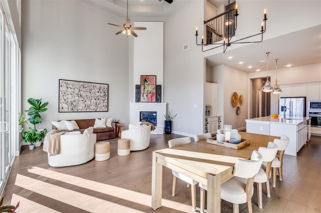 ****PRICE IMPROVEMENT**** Stunning Highland home in Trinity Falls offering 4 bedrooms, 5 bathrooms, and a 3-car tandem garage with EV charging. This light-filled, open-concept design features white oak flooring, vaulted wood-beamed ceilings, a floor-to-ceiling fireplace, and a dramatic two-story wall of windows with sliding glass doors. The chef’s kitchen includes white cabinetry, quartz countertops, an oversized island, and seamless flow into the dining and living areas—ideal for everyday living and entertaining. Sliding doors extend the living space to a covered patio with gas line for a future outdoor kitchen or firepit, plus landscaped grounds with raised garden beds. The primary suite is a private retreat with a spa-style bathroom featuring a freestanding soaking tub, walk-in shower, dual vanities, and marble finishes. The first floor also offers a dedicated home office, secondary en-suite bedroom, mud bench, and utility room with sink and cabinetry. Upstairs includes two additional bedrooms, a spacious game room, and a separate media room with dry bar—perfect for movie nights or hosting guests. Additional upgrades include tray and vaulted ceilings, mostly 8-foot interior doors, Ring doorbell and camera, transferable Starlink internet, sealed driveway, and custom walkway. Conveniently located near Frazier Elementary and the Trinity Falls amenity center, this home combines thoughtful design, modern upgrades, and access to resort-style community features.