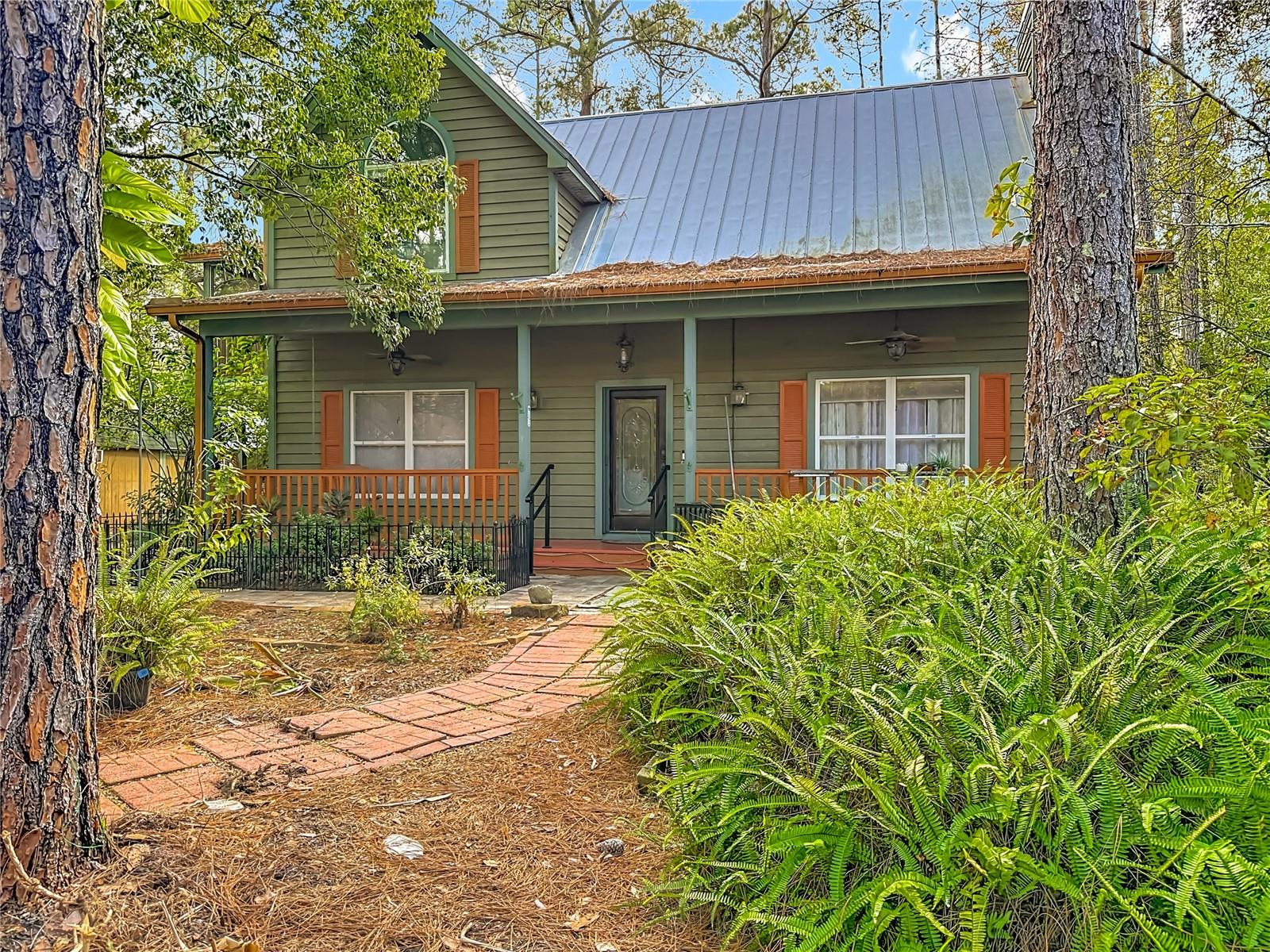 Escape the ordinary and discover a rare blend of country charm, privacy, and convenience. This home sits on a full 1 ACRE OF LUSH WOODED PRIVACY. AND NO HOA or CDD fees. Featuring 3 Bedrooms, 2 Full Bathrooms, Huge Workshop and more....Tucked beneath a canopy of mature trees, this unique two-story home offers a peaceful, rural feel—yet is only minutes from all the shopping, dining, and conveniences of Wesley Chapel.A welcoming full-length front porch invites morning coffee and quiet evenings, while the entire rear patio spans the back of the home, creating effortless indoor-outdoor living. Meandering paver walkways and paths wind through the naturally preserved landscape, offering space to breathe, explore, and truly unwind.Inside, the layout showcases the vaulted ceilings and windows allowing for an abundance of natural lighting and air circulation.  The private primary suite is located upstairs including an ensuite bath and two balconies—one covered and one open—perfect for enjoying the treetop views. Downstairs, two bedrooms are connected by a Jack-and-Jill style bath, ideal for family, guests, or home office needs. The kitchen is equipped with stainless steel appliances, a cozy breakfast nook, and inside laundry, making daily living comfortable and functional.For hobbyists, entrepreneurs, or those needing serious storage, this property truly shines. A large workshop with electricity and window A/C, a second powered workshop/shed, and a lean-to for outdoor equipment provide endless possibilities—whether for projects, storage, or business use. Additional highlights include a METAL ROOF, NEWER A/C (2024), an attached carport, and two space concrete parking pad.With a little personalization, for you this is more than a home—it’s a lifestyle opportunity where privacy, space, and freedom meet convenience. If you’ve been searching for room to live, work, and breathe without sacrificing proximity to town, this is one you need to experience in person.