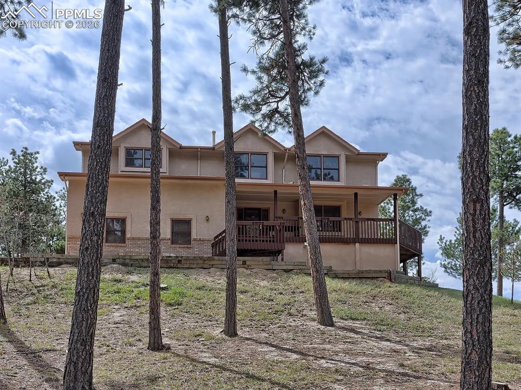 Tucked into the quiet Woodmoor community near the golf course, this spacious home offers a rare blend of comfort, privacy, and scenic beauty—perfect for those who appreciate a wooded setting with stunning views of Pikes Peak.Designed with both everyday living and entertaining in mind, the home features an inviting flow and expansive windows that bring the outdoors in. A welcoming front porch sets the tone, while multiple decks provide ideal spots to relax and take in the natural surroundings.The generously sized primary suite serves as a true retreat, with space for a sitting area or workspace, a cozy fireplace, access to a private deck, and an oversized bathroom. Upstairs, three additional bedrooms and conveniently located laundry add to the home’s functional layout.The lower level expands the living space even further, offering a large family room, an additional bedroom, full bathroom, office area, built-in cabinetry, and room for a kitchenette—plus a pellet stove for added warmth and character.Additional highlights include a mudroom off the garage, a sunroom perfect for plants, a hot tub for unwinding, abundant storage throughout, and beautiful wood flooring.This home does need some updates and is being sold as-is, with pricing that reflects the opportunity—making it an excellent choice for buyers looking to personalize a home in a peaceful, view-filled setting.