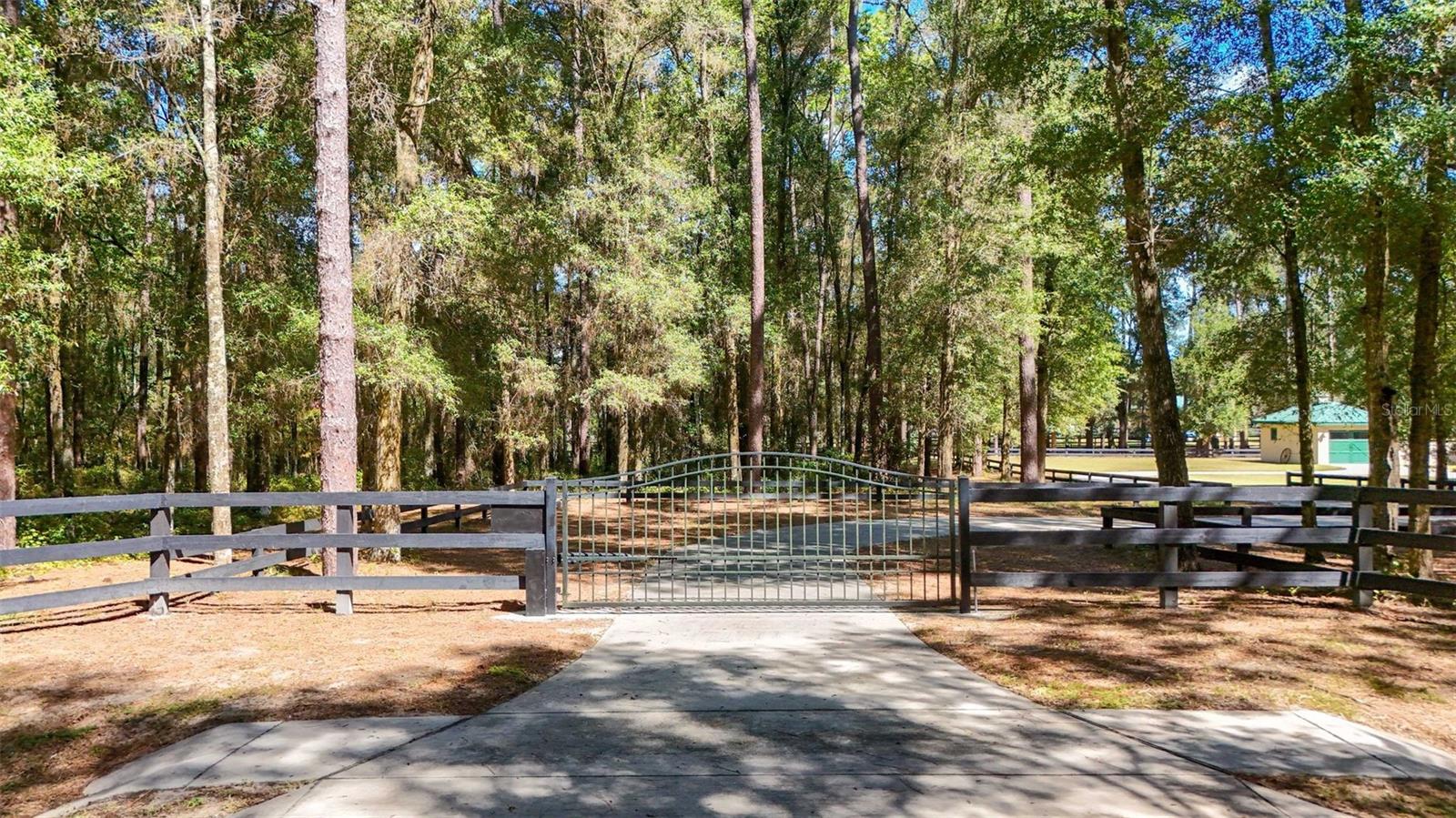 An automatic gate opens to a winding concrete driveway leading toward a contemporary Craftsman ranch set on 4.7 acres in Meadow Wood Farms. It is an arrival that immediately changes the pace—peaceful and distinctly country, with granddaddy oaks, open fenced and cross-fenced pasture areas, and wooded sections that give the property a sense of depth and separation. Inside, the story turns to craftsmanship and an owner's passion for woodworking. True Pennsylvania old-growth hickory wide-plank floors bring warmth and character throughout the home, complemented by substantial knotty alder interior doors and window trim, beautifully crafted cabinetry and a handcrafted coffered ceiling in the living room. Ten-foot ceilings, double-tray details and generous glass add volume and natural light to the living areas, while the kitchen pairs extensive wood cabinetry with granite countertops and plenty of room for gathering. These are details meant to be noticed—not because they are trendy, but because of the materials and workmanship behind them. Quality extends beyond the finishes, with additional steel and concrete in the foundation, upgraded double-pane windows and a commercial-grade metal roof with a baked-on finish—choices made with the years ahead in mind. Two detached front-entry garages add storage and flexibility, while underground electric keeps utility lines from interrupting the country landscape. A separate 900-square-foot block-and-stucco workshop expands the possibilities, with two oversized roll-up doors, heavy-duty loft, electric, water and an adjoining concrete equipment pad. Whether your interests run to cars, woodworking, equipment or another serious hobby, there is room to make it your own. In an area known for gentleman horse farms, the building has flexibility to adapt to future equestrian needs, with board fencing, cross fencing and designated pasture areas already part of the landscape. Here, the pleasures extend well beyond the walls of the home. Open pasture, magnificent old oaks and pockets of woods create an idyllic backdrop for country living, while Meadow Wood Farms places you within easy reach of the World Equestrian Center and HITS. A distinctive setting, enduring materials and craftsmanship come together in a property meant to be experienced from the moment you turn through the gate.